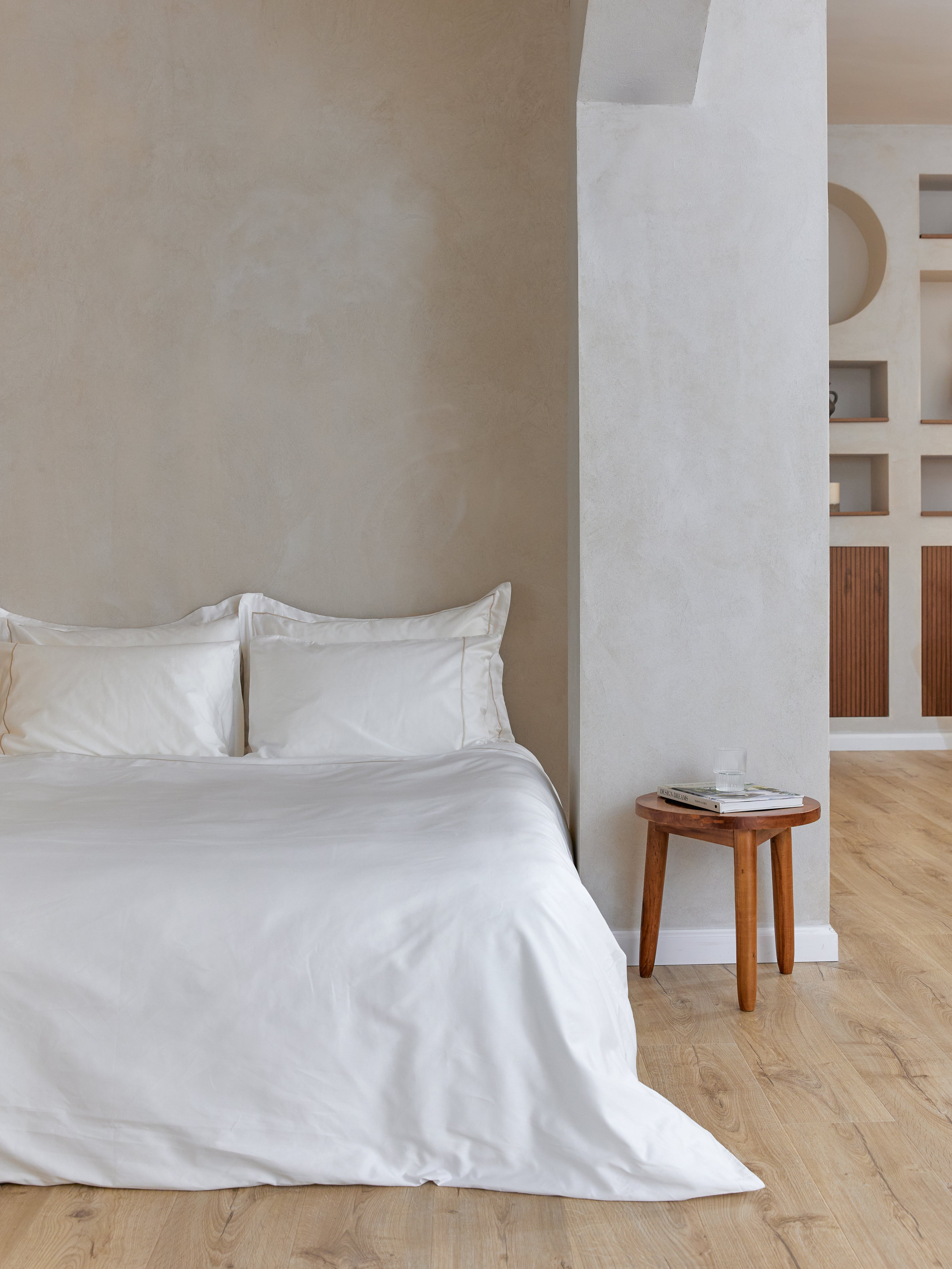 סט מצעים לבנים עם מסגרת פארטו בצבע שמפניה, על מיטה זוגית