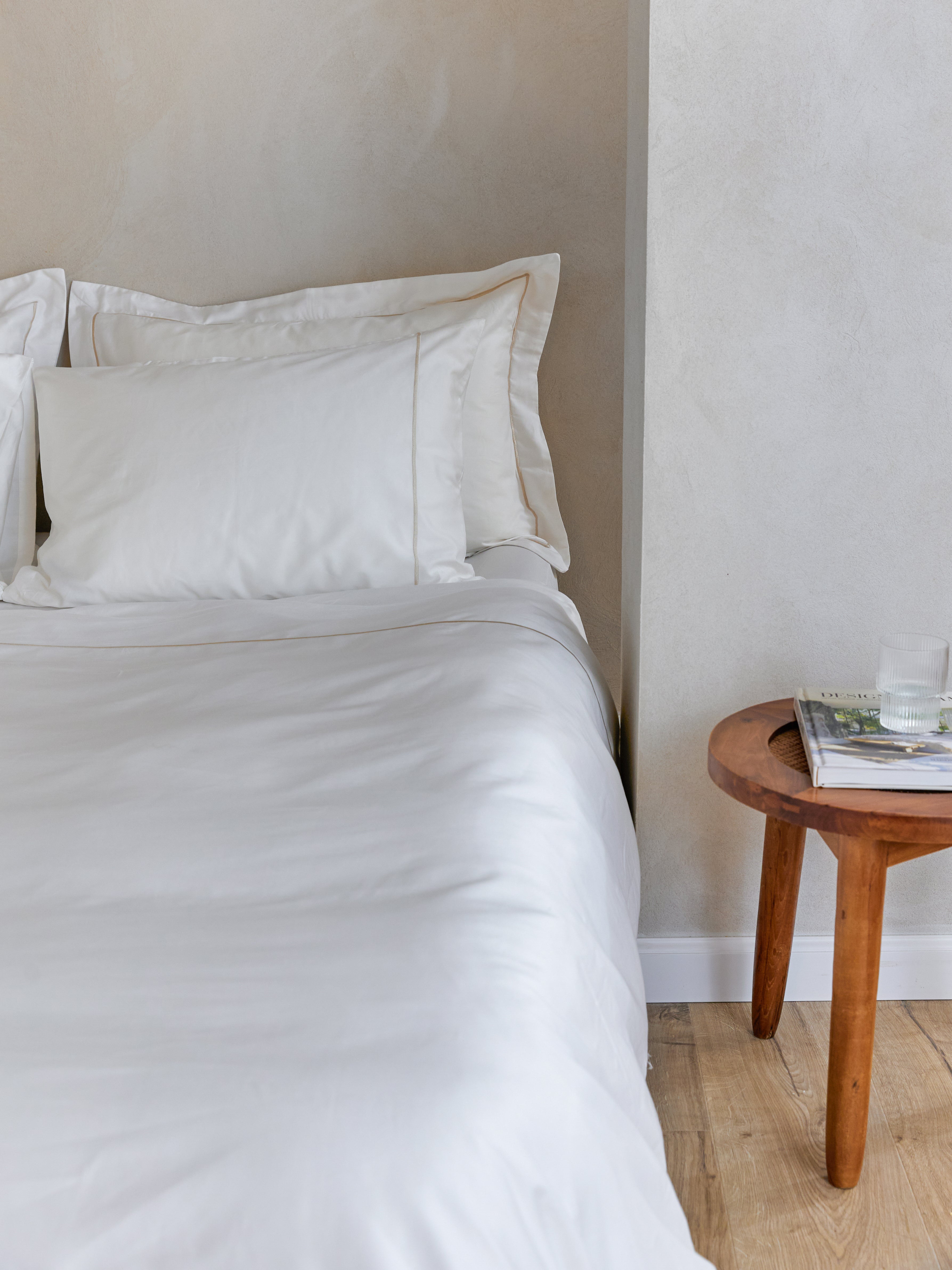 תקריב מיטה זוגית עם מצעי סאטן לבנים עם מסגרת פארטו בצבע שמפניה