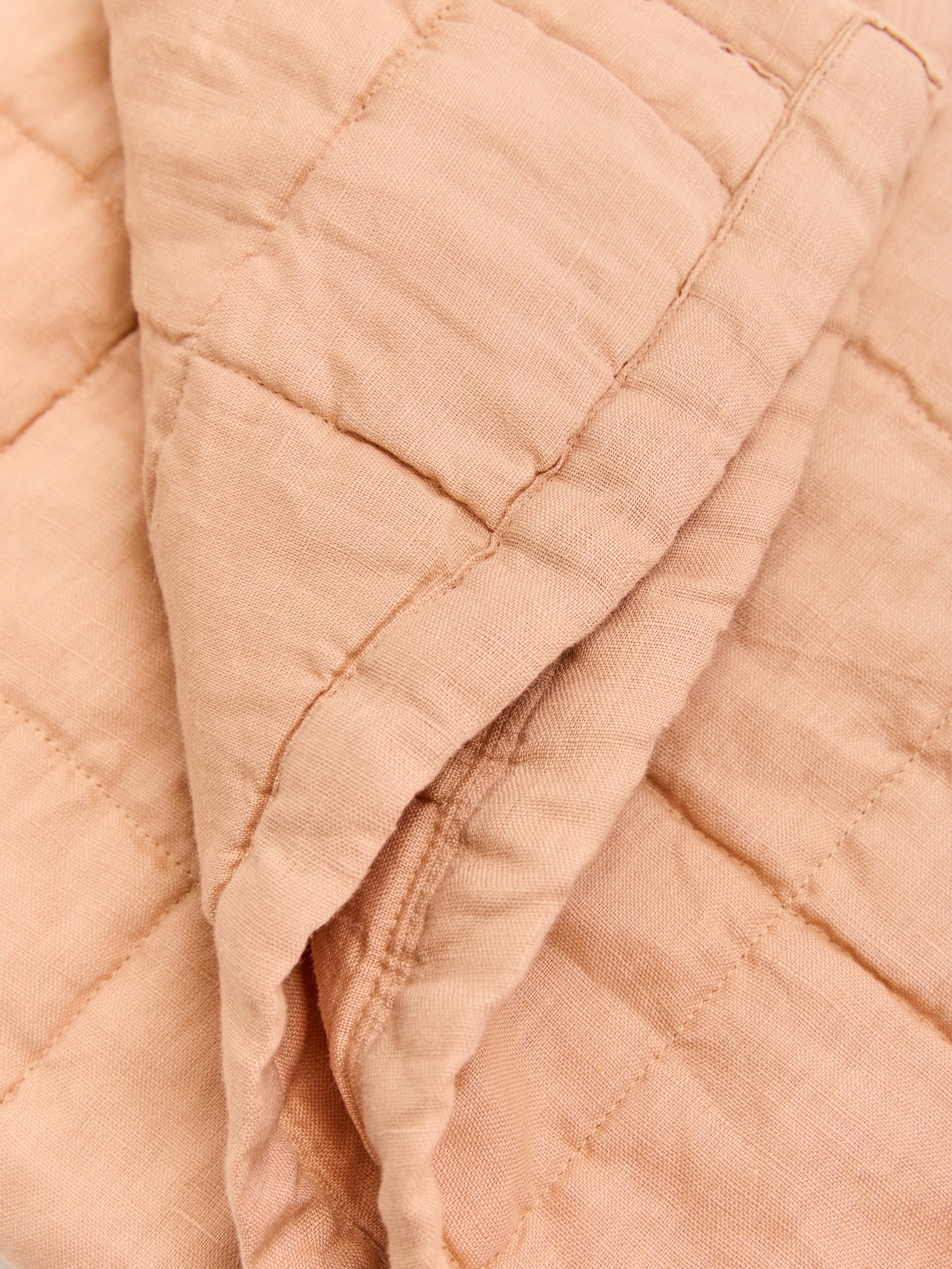 תקריב של שמחת קווילט מפשתן בצבע ורדרד מקופלת