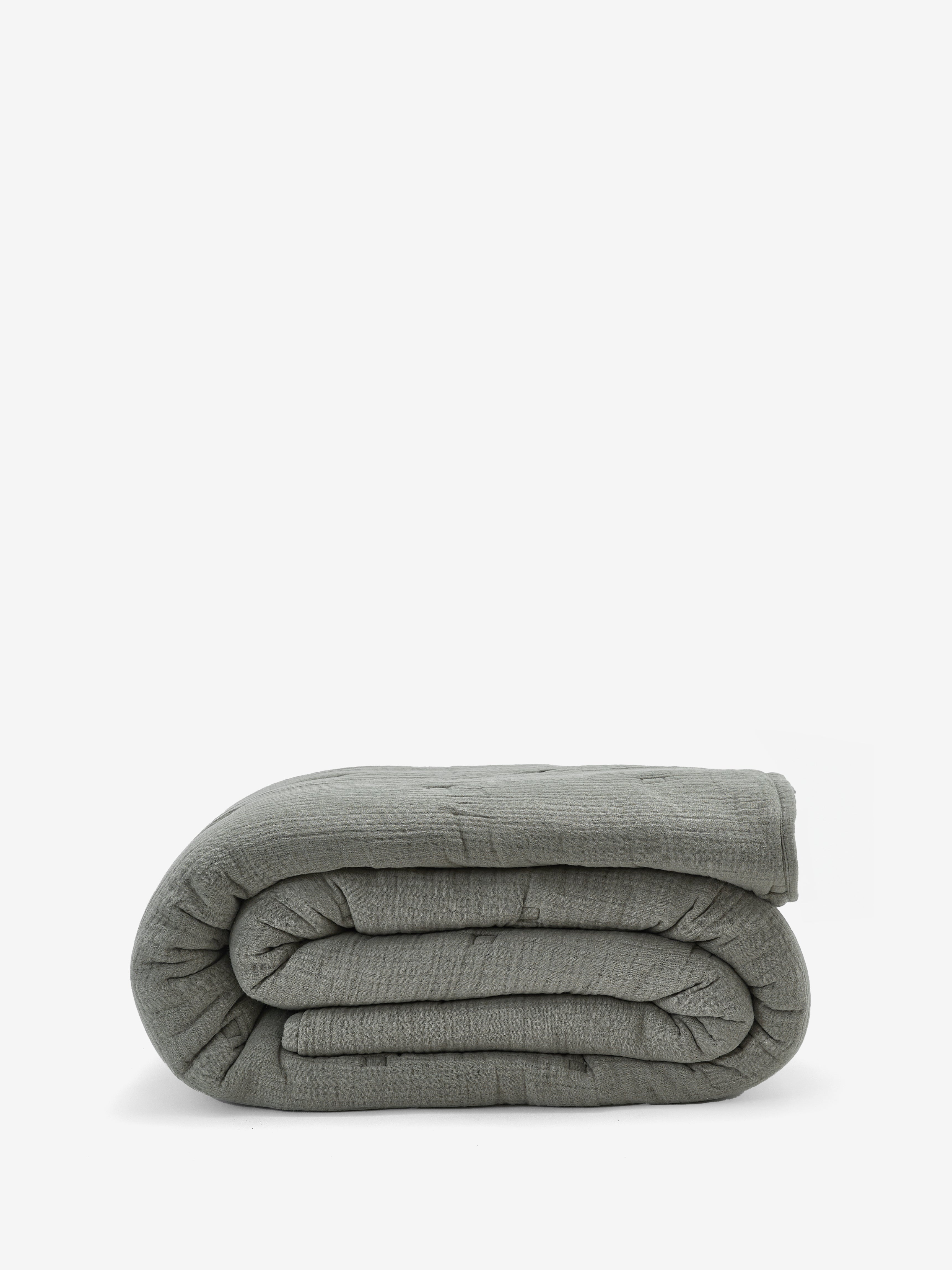 שמיכת פוך מוסלין בצבע ירוק מרווה מקופלת על רקע לבן