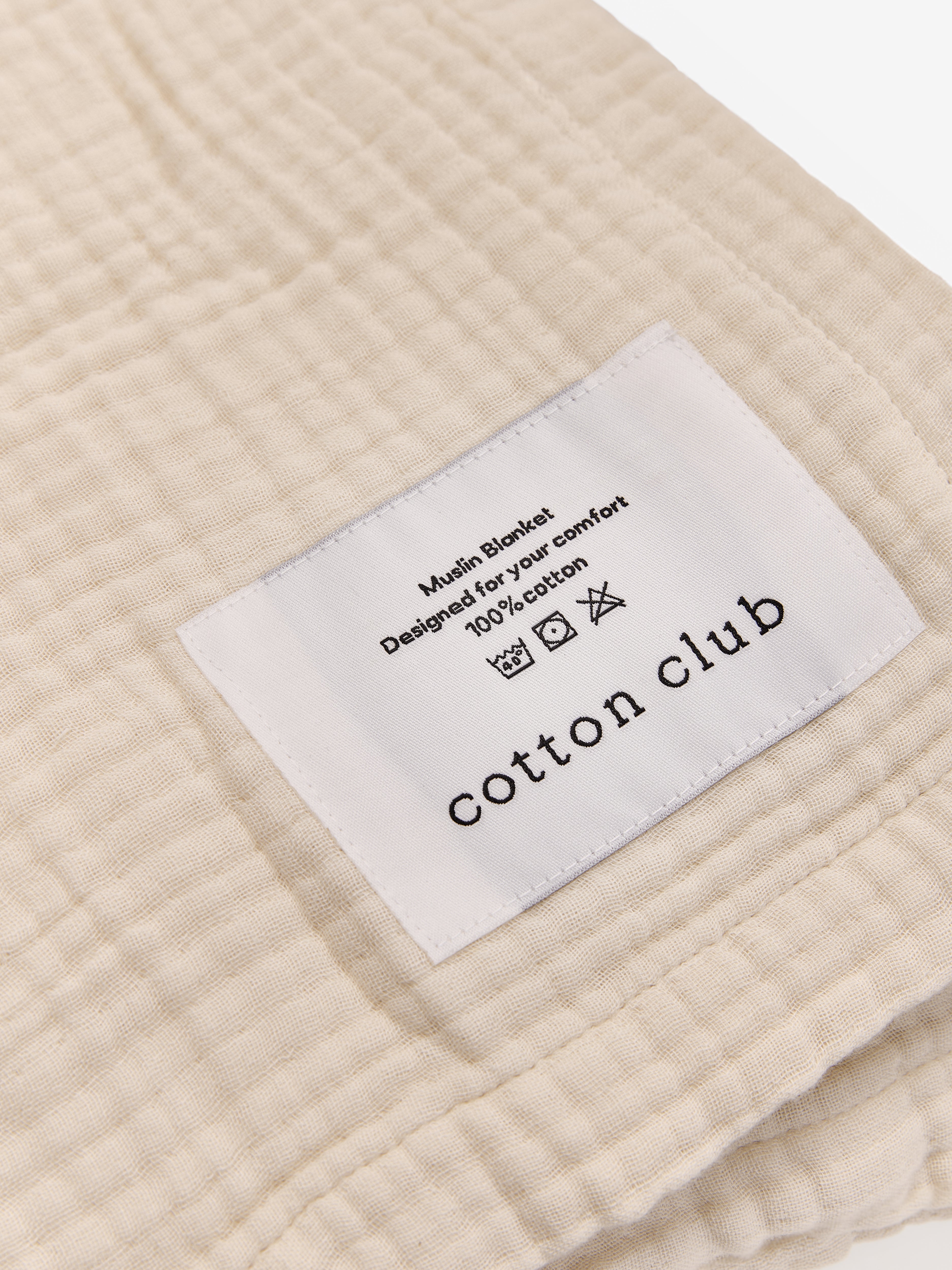 טיקט לוגו תפור על שמיכת מוסלין בצבע קרם