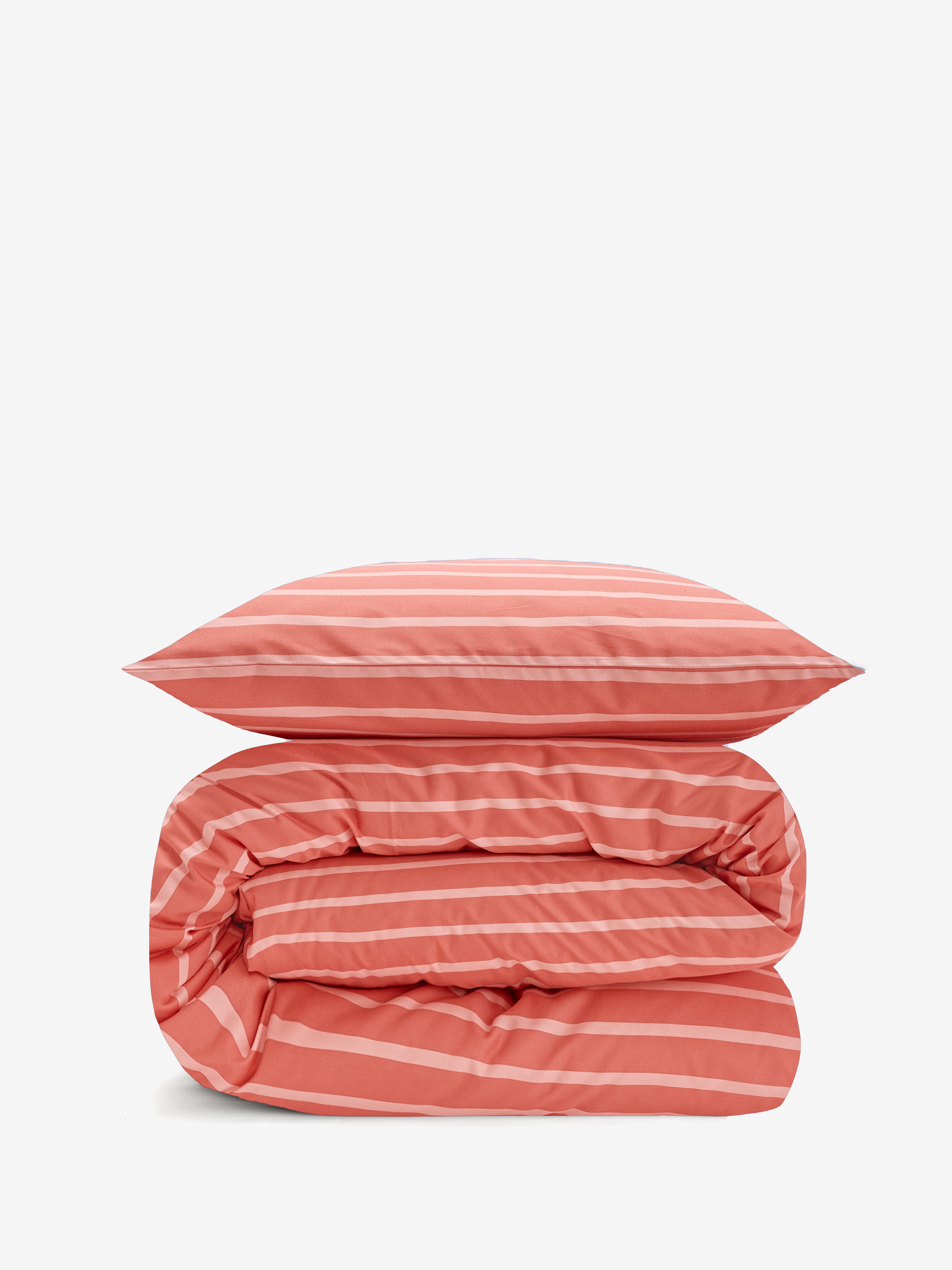 סט מצעי כותנה בצבע אפרסק כהה עם פסים בצבע אפרסק בהיר, שמיכה מגולגלת ומעליה כרית