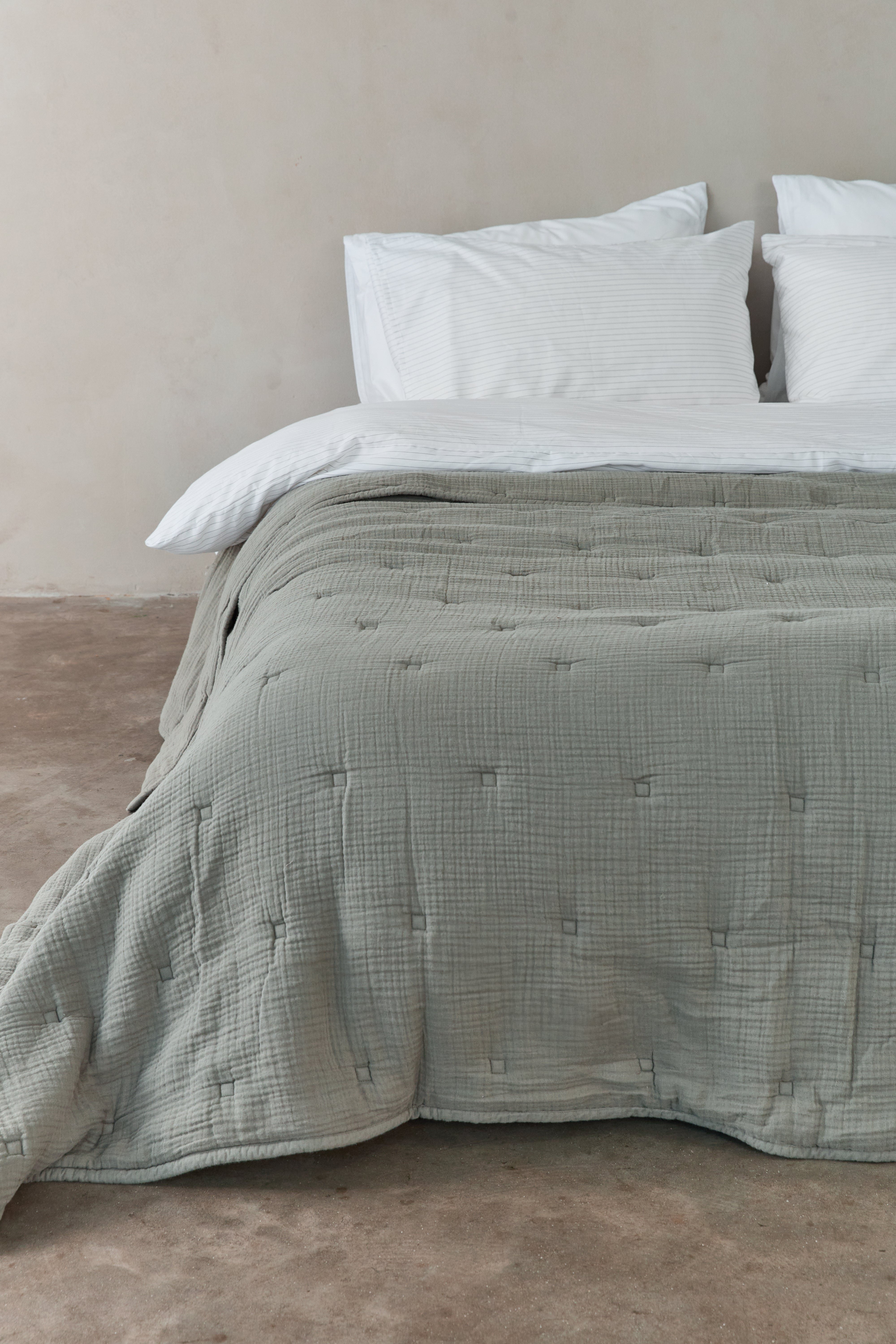 שמיכת פוך מוסלין בצבע ירוק מרווה פרוסה על מיטה זוגית עם מצעים לבנים