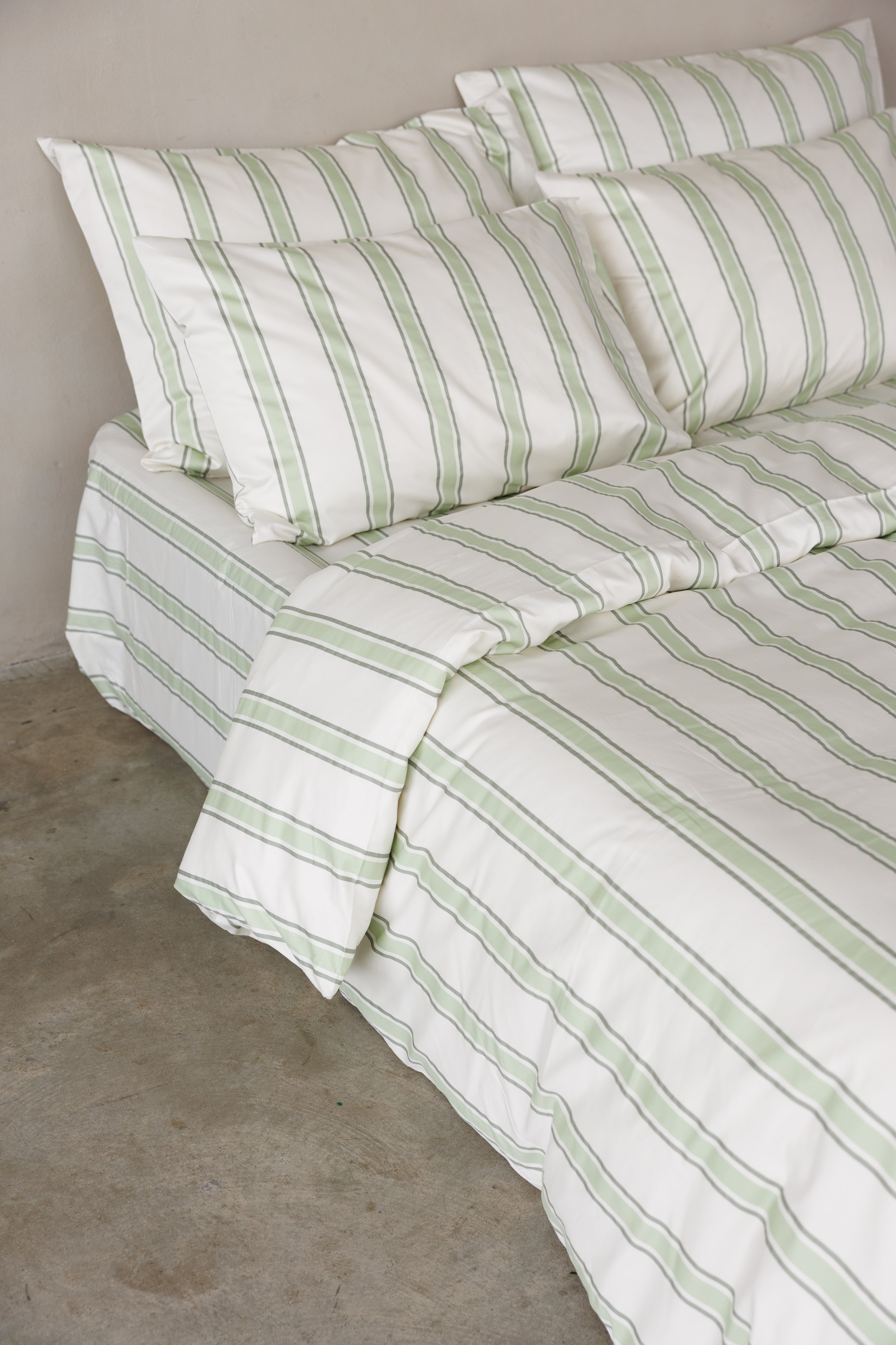 פינה של מיטה זוגית עם מצעי סאטן 500 צבע לבן עם פסים עבים בירוק בהיר ופסים דקים בירוק כהה יותר
