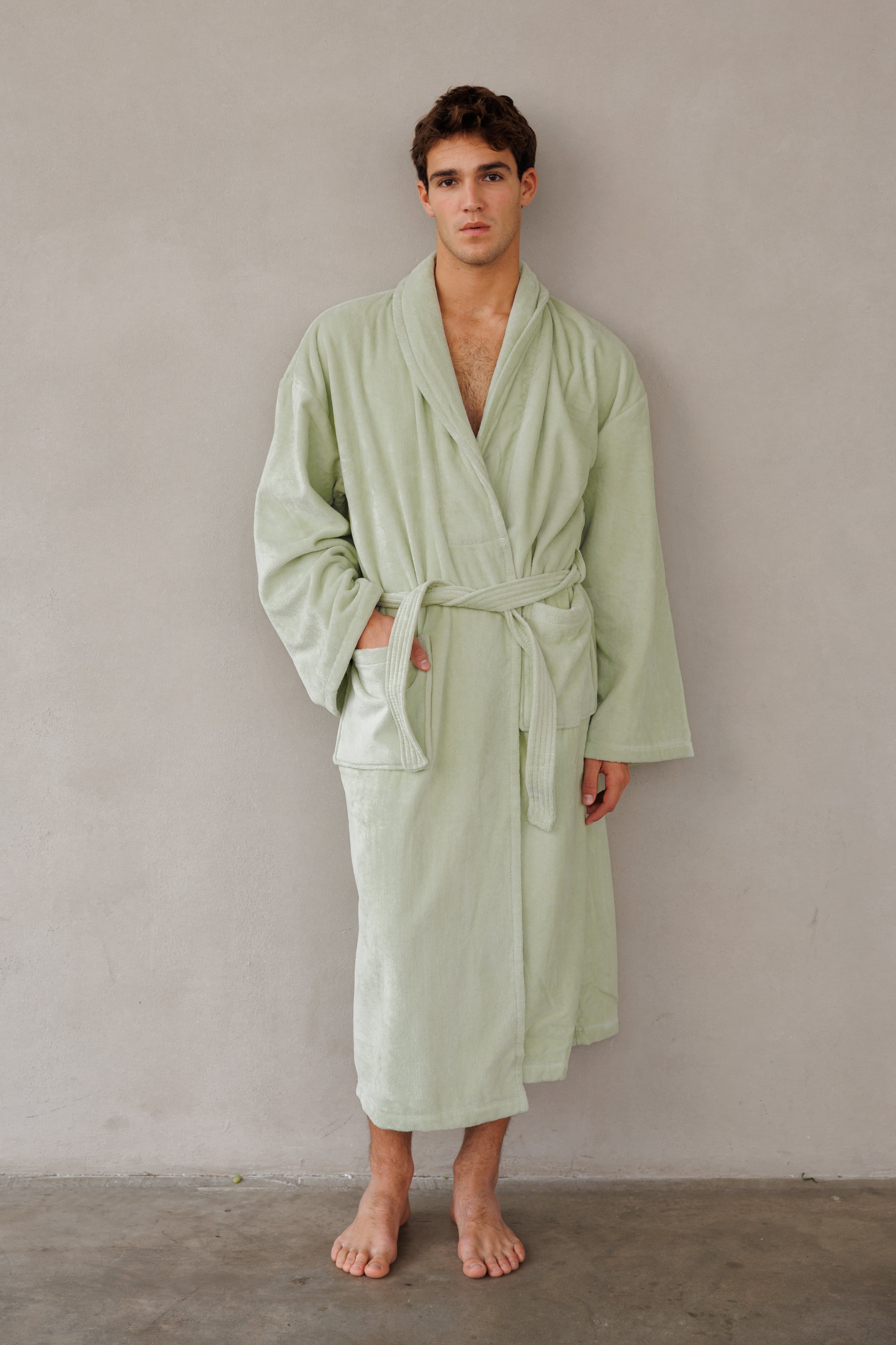 דוגמן עומד כנגד קיר עם חלוק קלאסי בצע ירוק ליים ומכניס יד לכיס