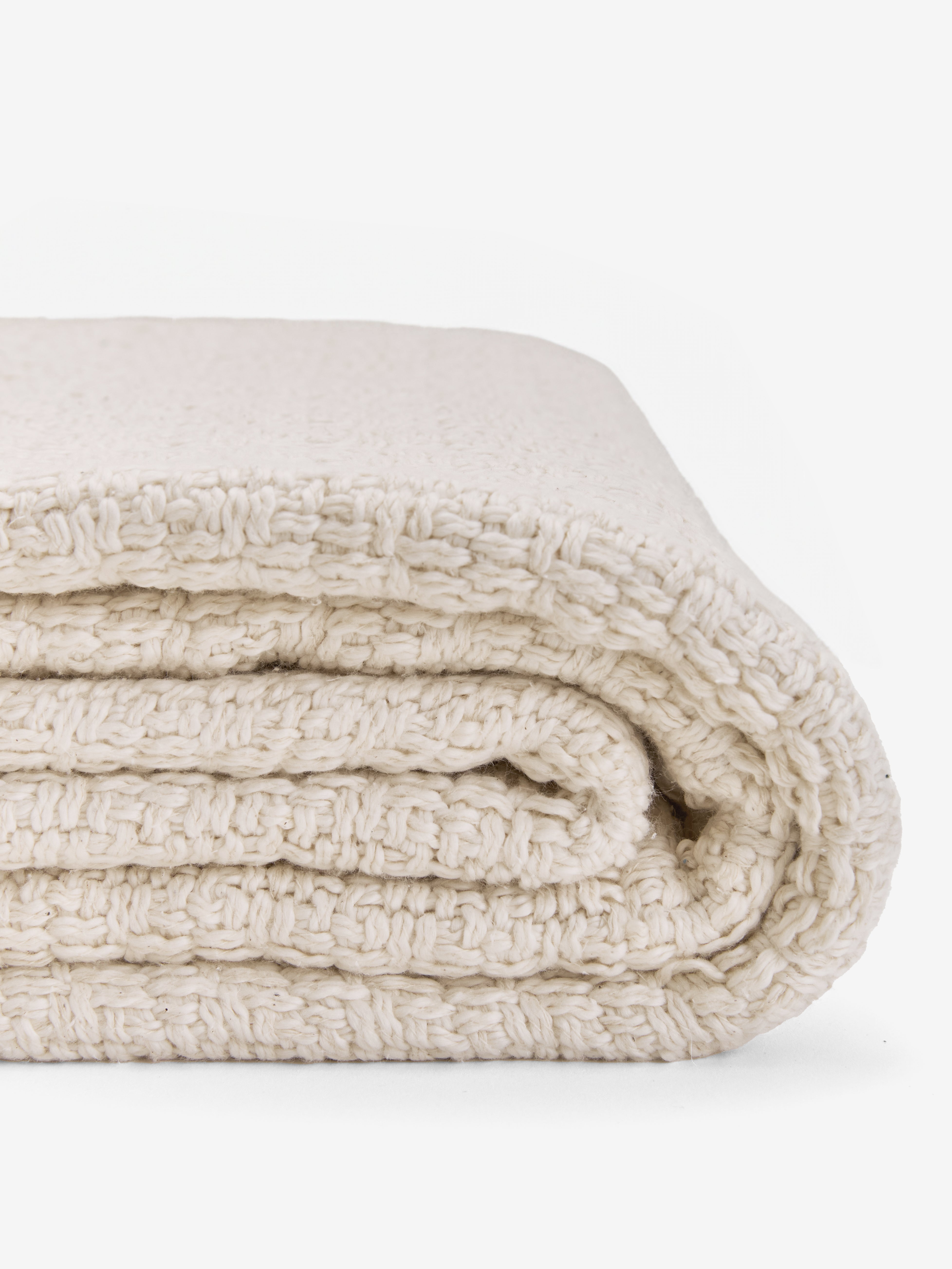 תקריב שמיכת נוי מקופלת, כותנה ארוגה בצבע שמנת