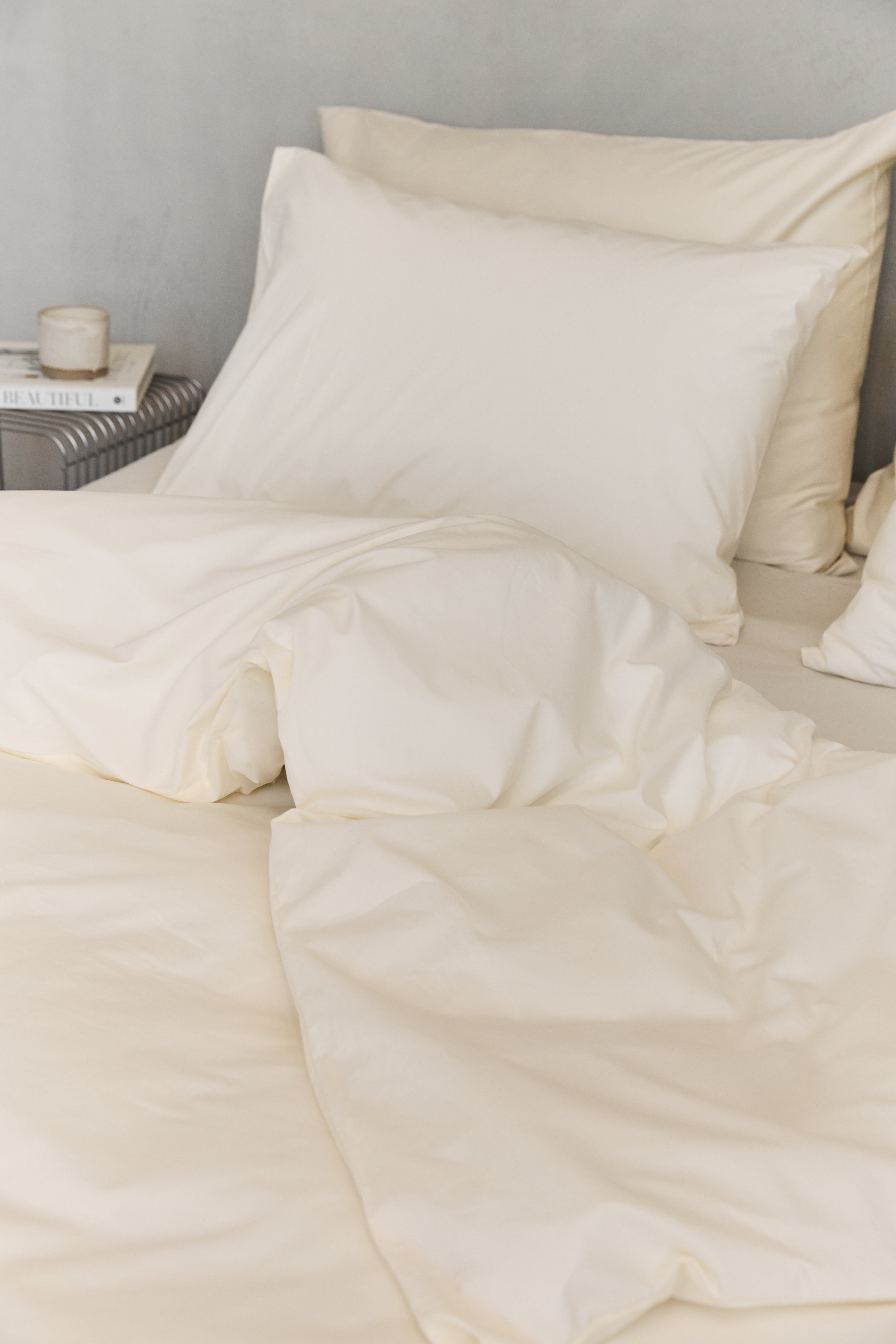 תקריב סט מצעי כותנה בצבע קרם, על מיטה זוגית