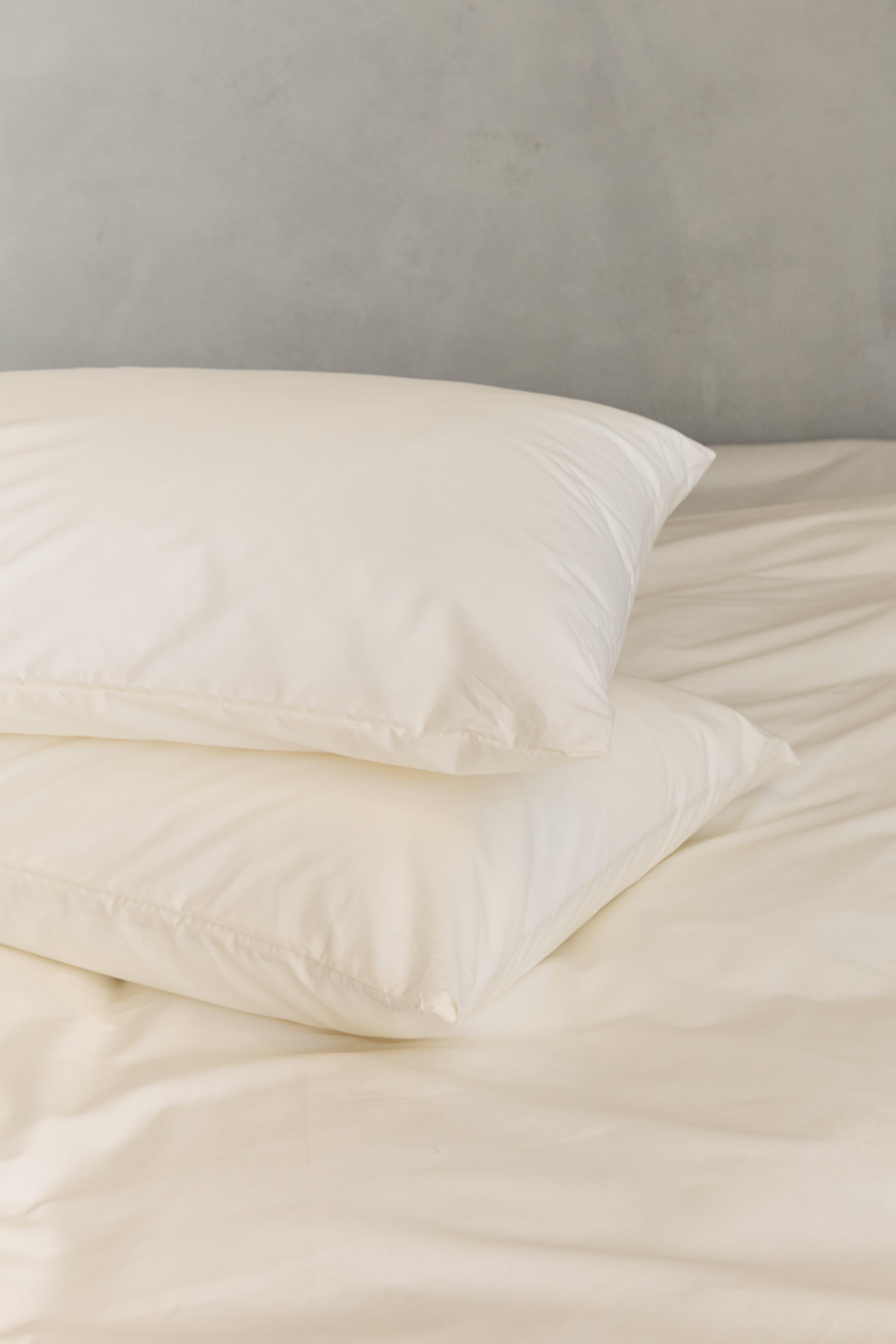 שתי כריות מונחות אחת על השניה עם ציפיות כותנה בצבע קרם