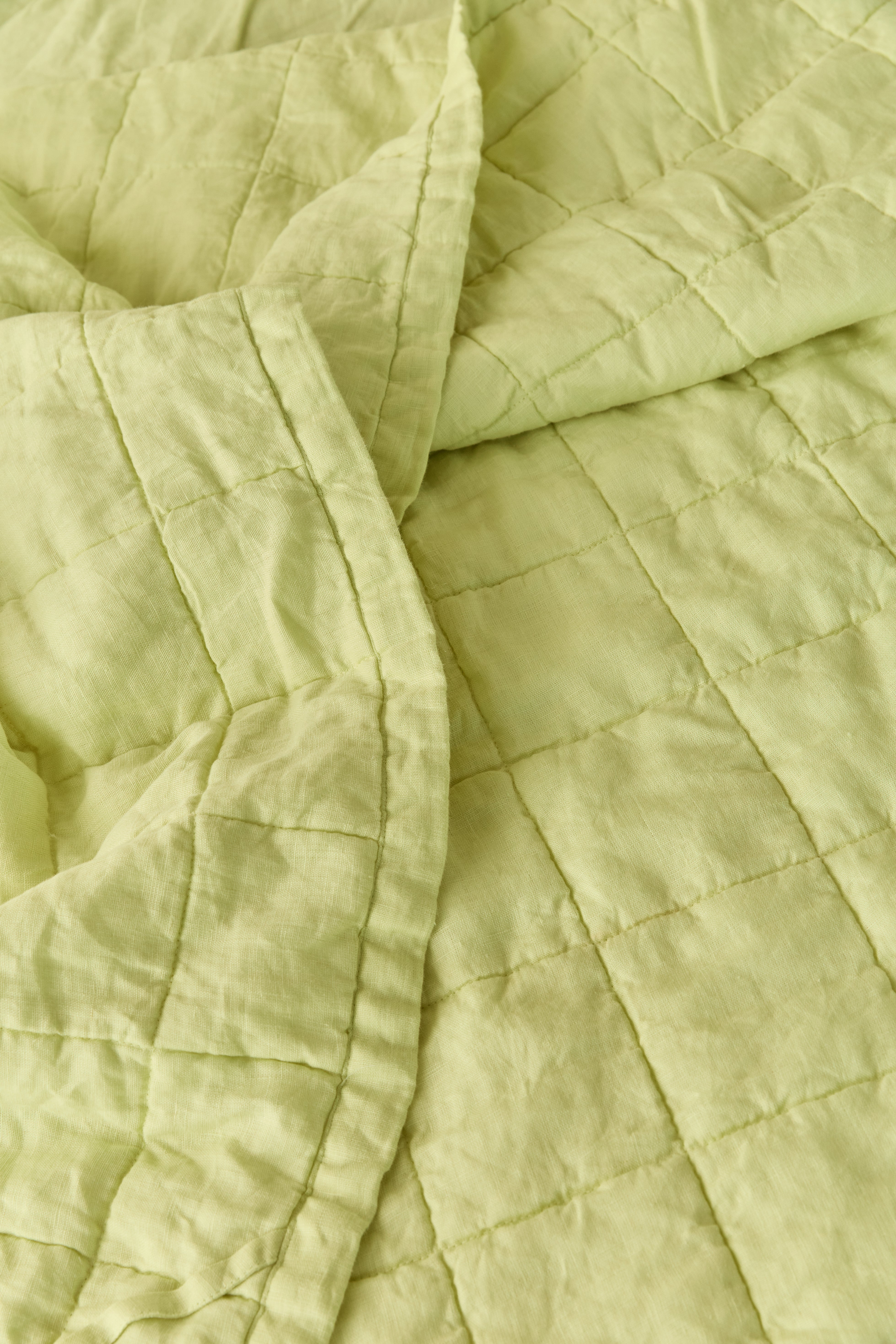 תקריב טקסטורה של שמיכת קווילט פשתן בצבע ליים