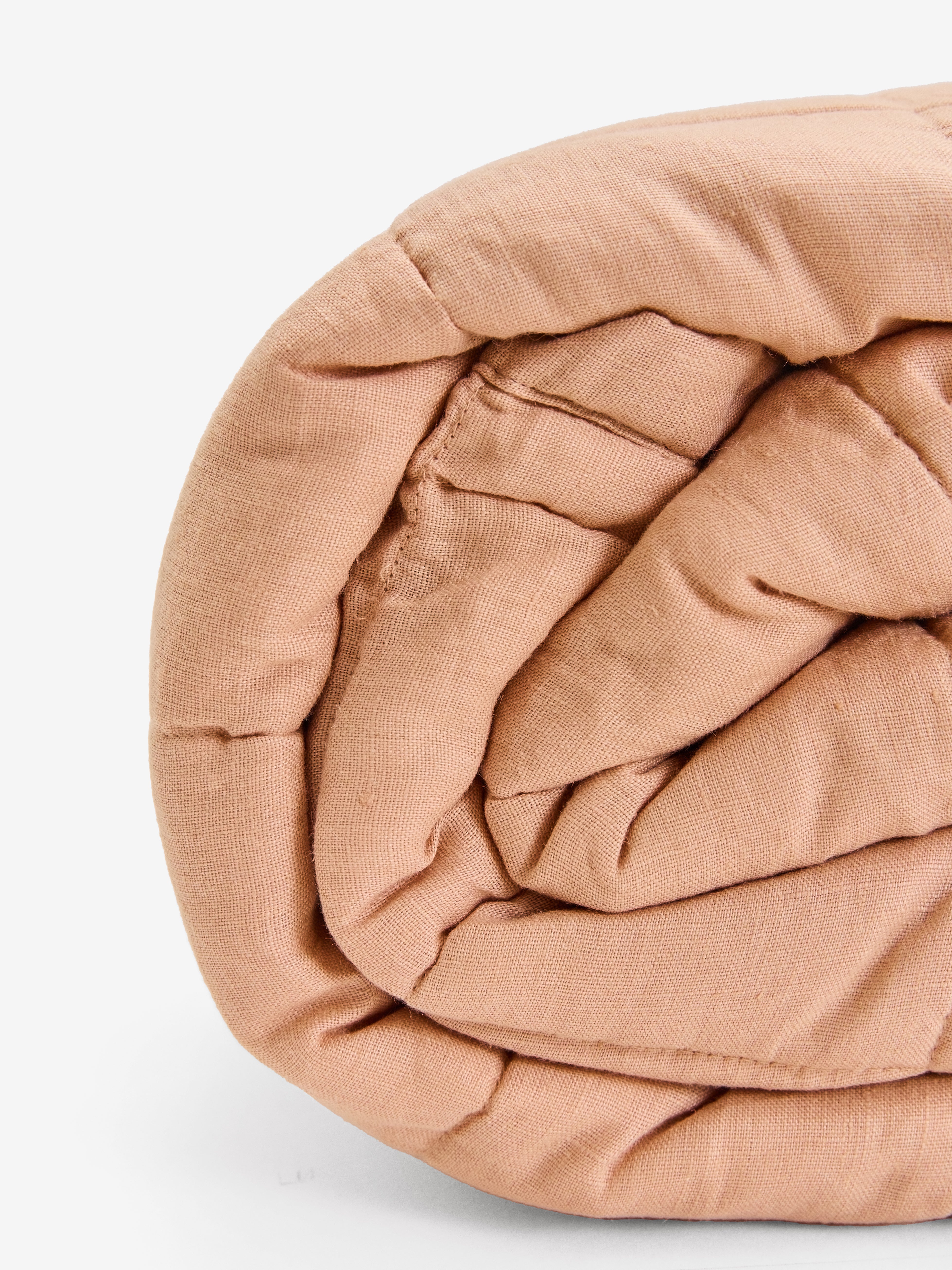 תקריב של שמיכת קווילט מפשתן בצבע ורדרד