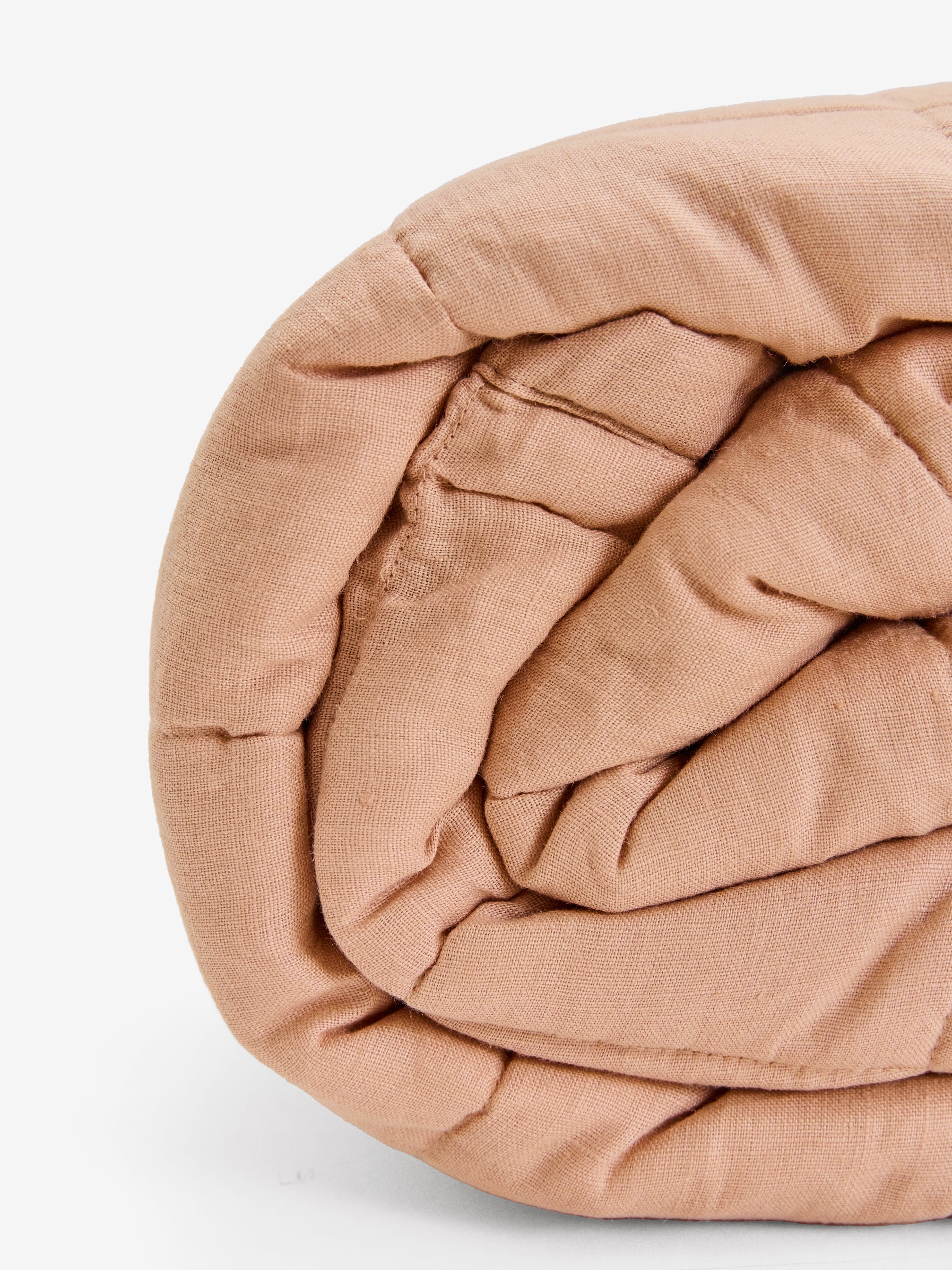 תקריב של שמיכת קווילט מפשתן בצבע ורדרד