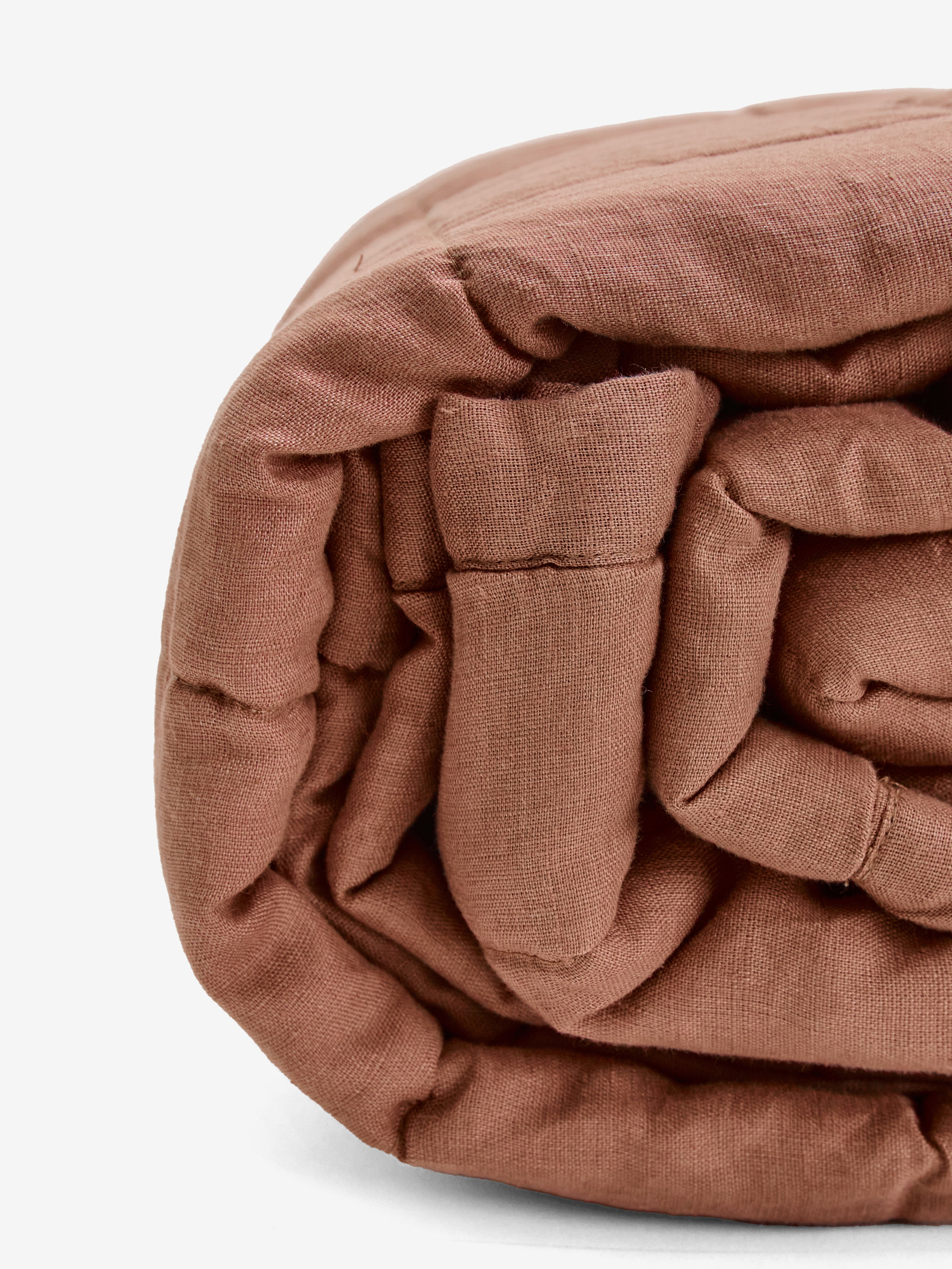 תקריב של שמיכת קווילט מפשתן בצבע מוקה