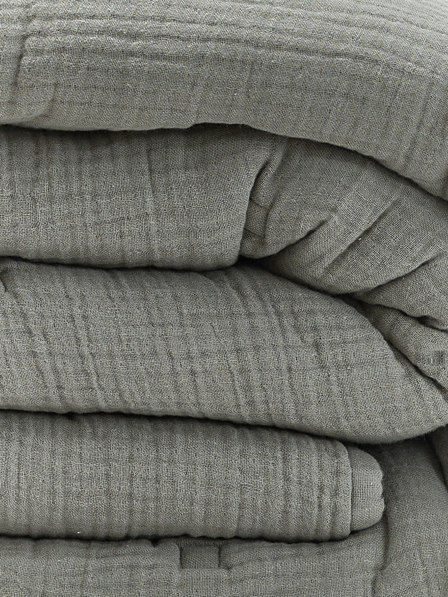 תקריב קפלים של שמיכת פוך מוסלין בצבע ירוק מרווה