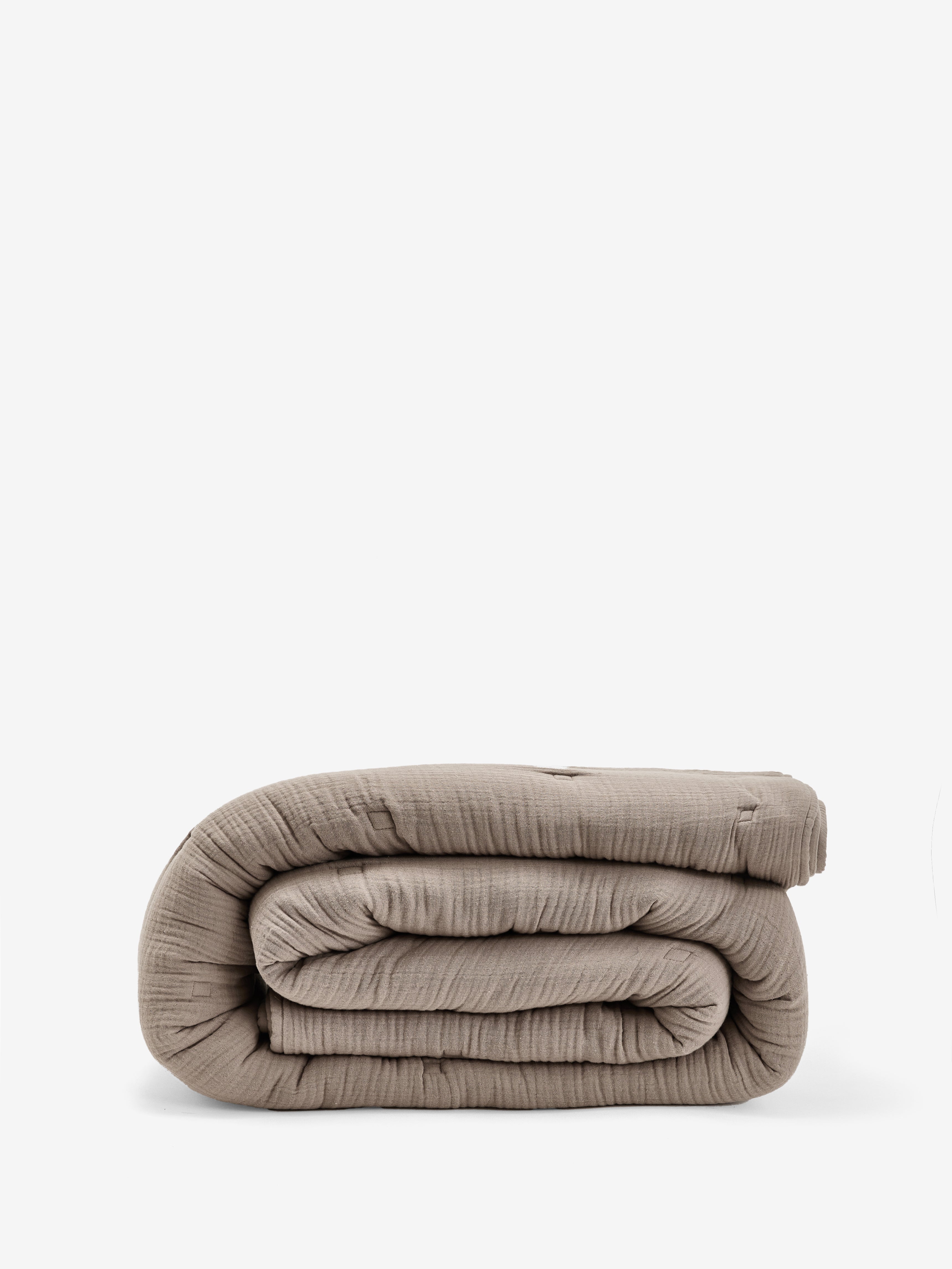 שמיכת פוך מוסלין בצבע מוקה מקופלת על רקע לבן