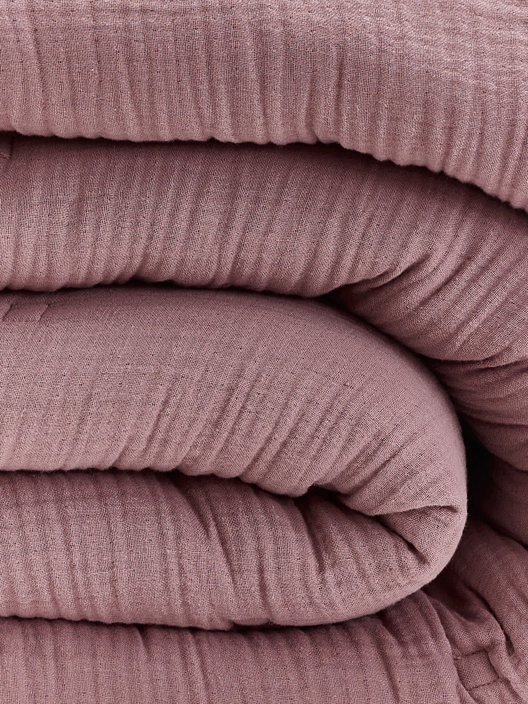 תקריב קפלים של שמיכת פוך מוסלין בצבע ורוד עתיק 