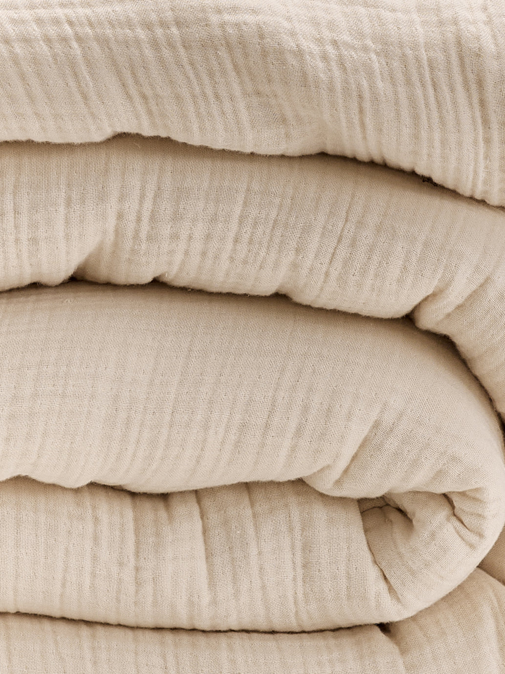 תקריב קפלים של שמיכת פוך מוסלין בצבע קרם