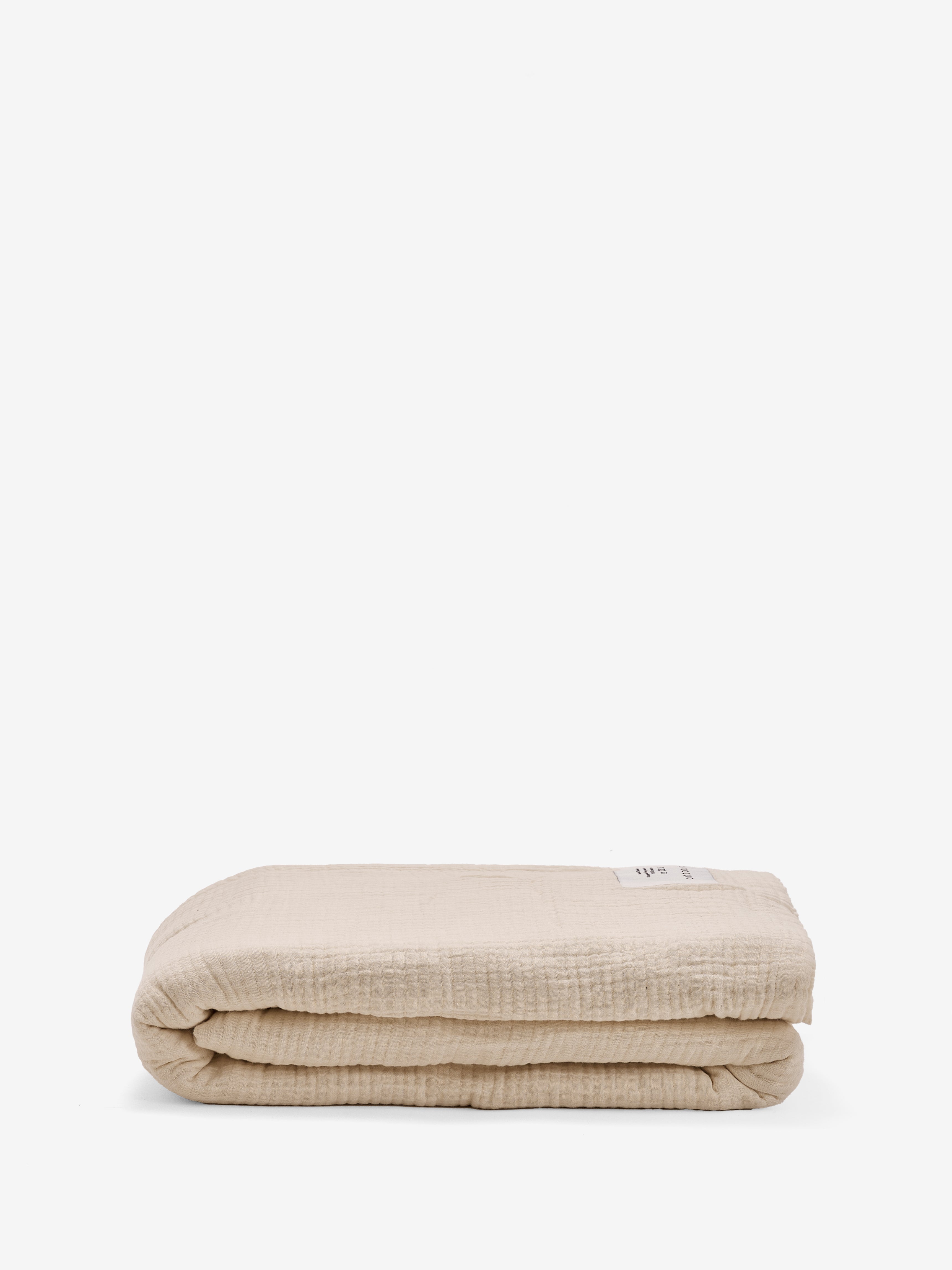 שמיכת מוסלין בצבע קרם מקופלת על רקע לבן