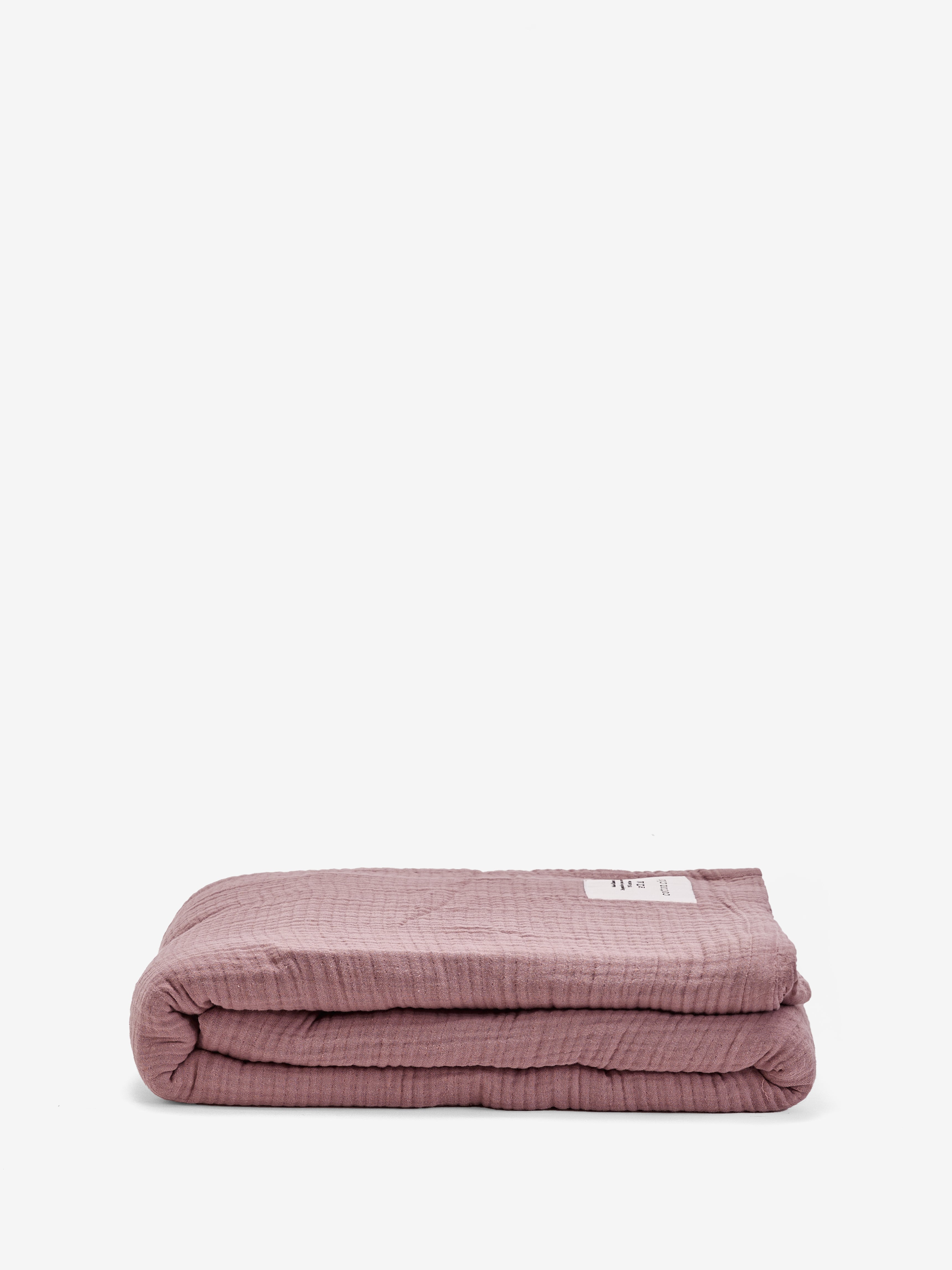 שמיכת מוסלין בצבע ורוד עתיק מקופלת על רקע לבן