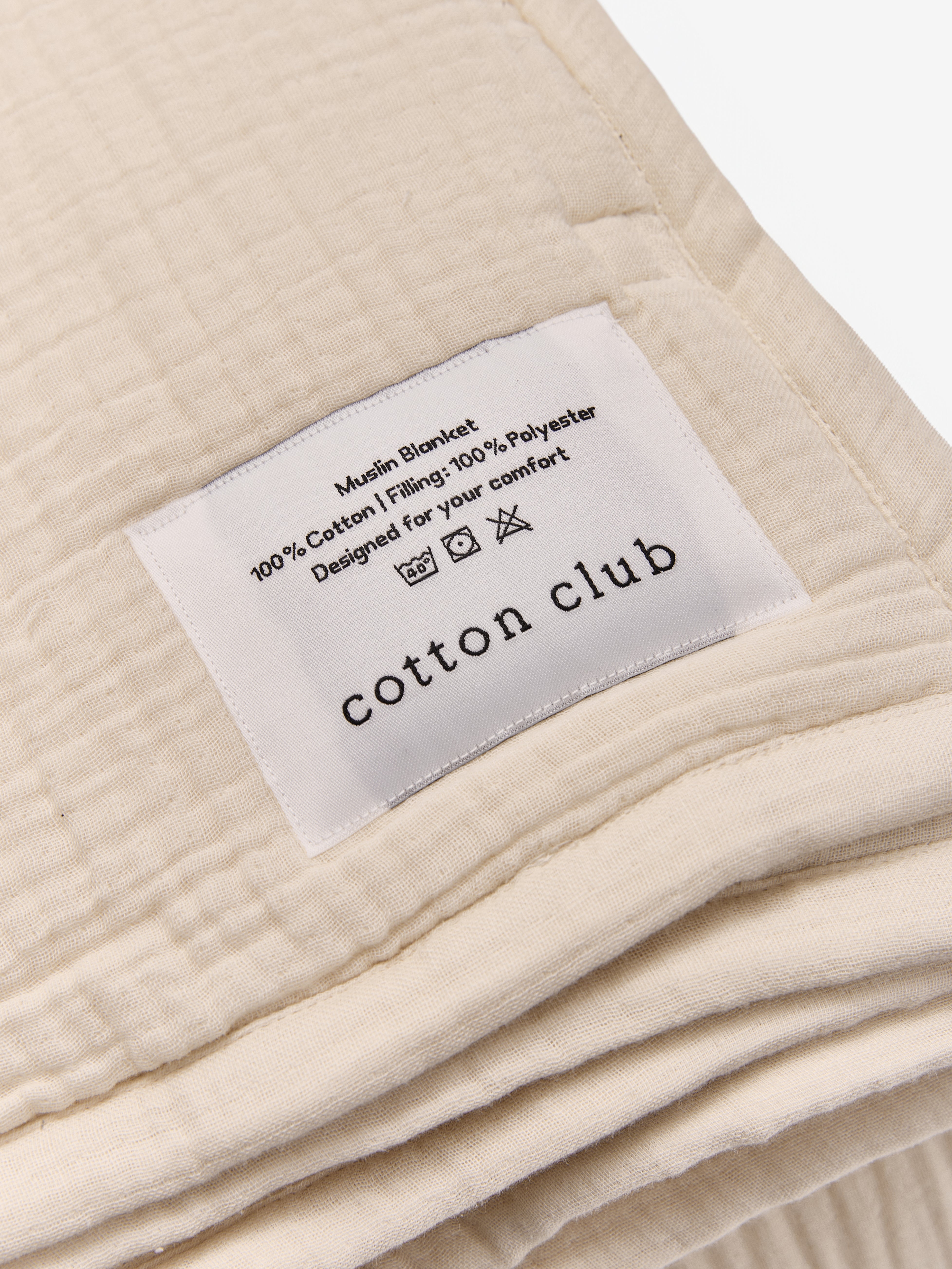 טיקט לוגו תפור על שמיכת פוך מוסלין בצבע קרם