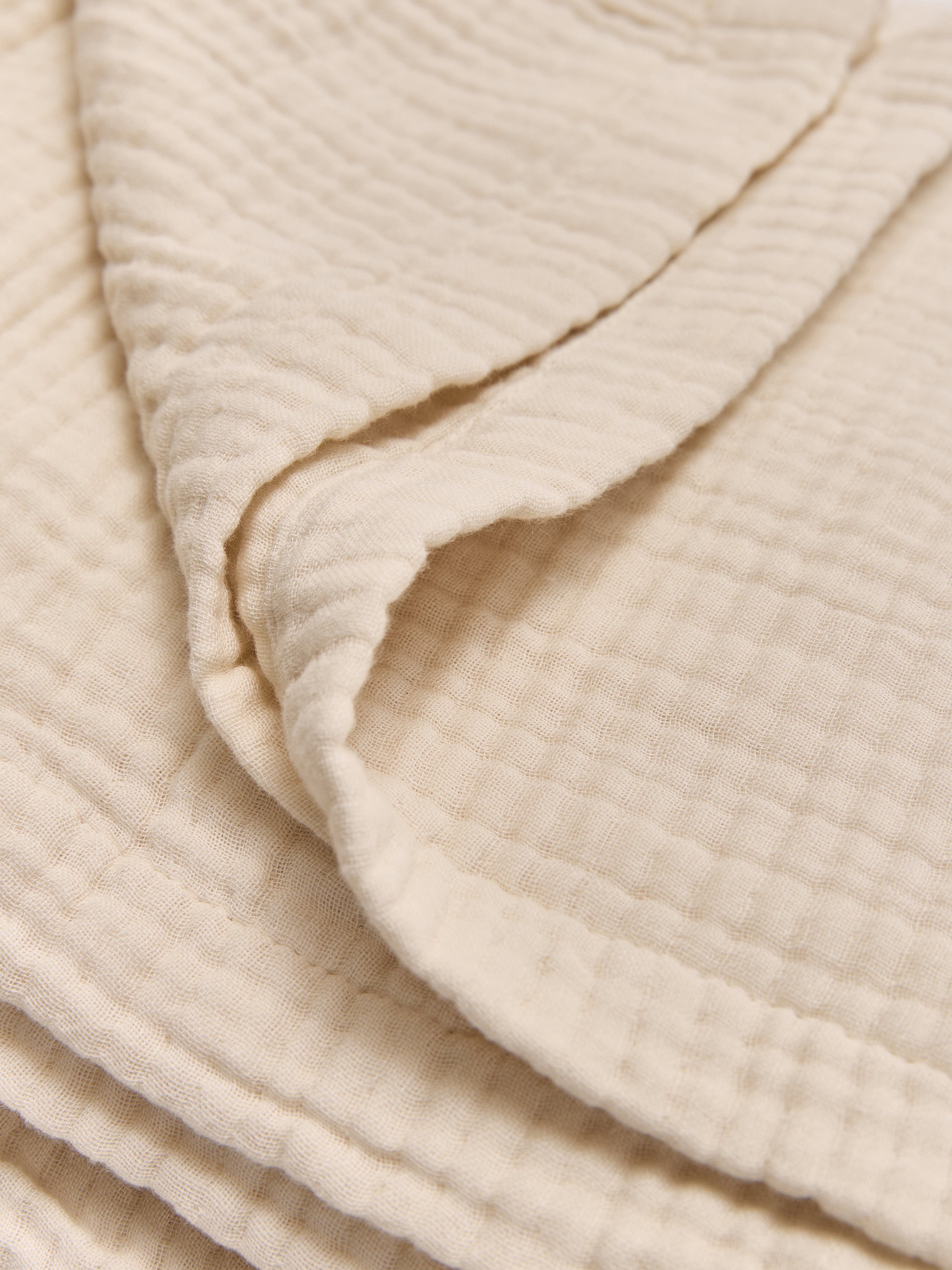 תקריב בד שמיכת מוסלין בצבע קרם 