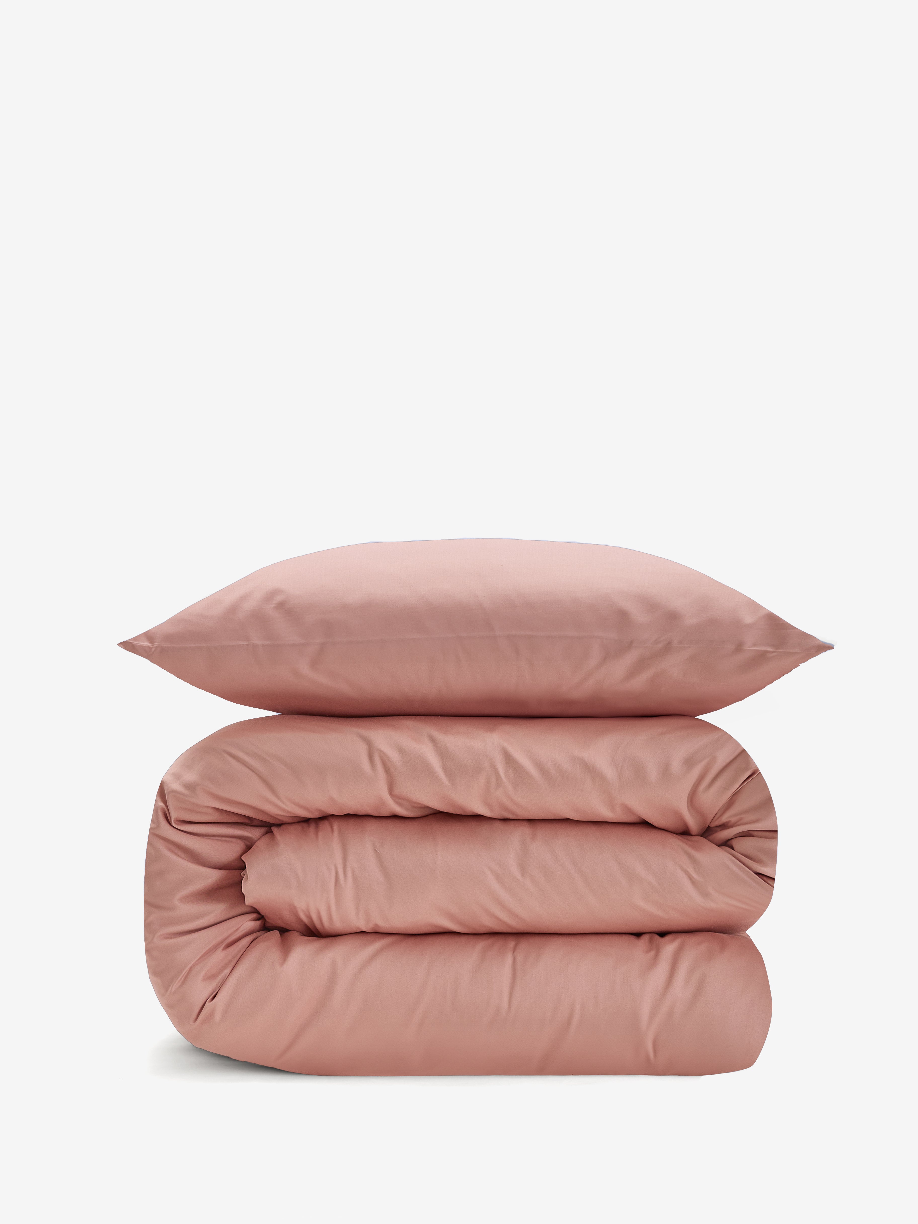 סט מצעי כותנה בצבע אפרסק, שמיכה מגולגלת וכרית מעליה