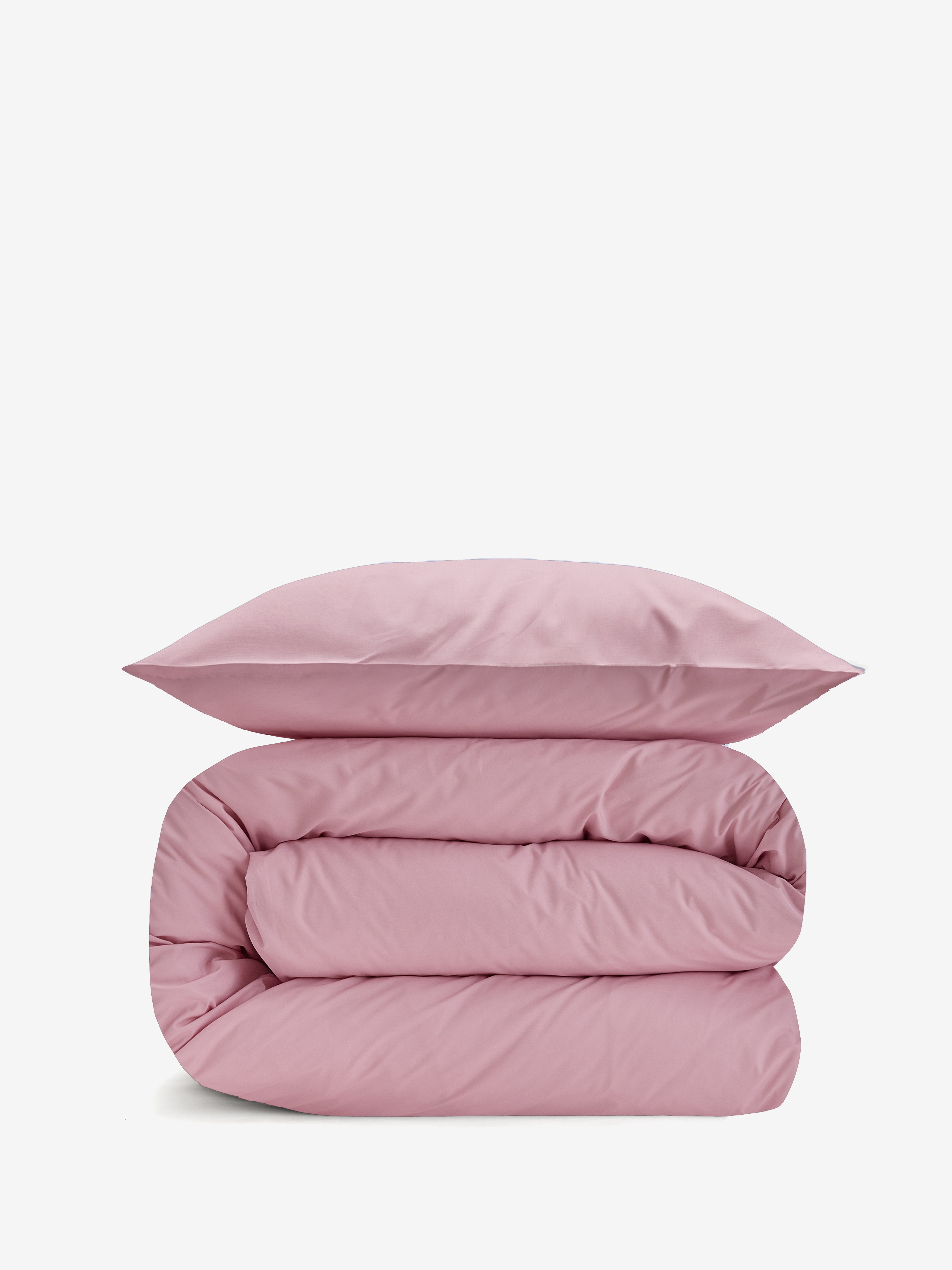 סט מצעי כותנה בצבע ורוד בהיר, שמיכה מגולגלת וכרית מעליה