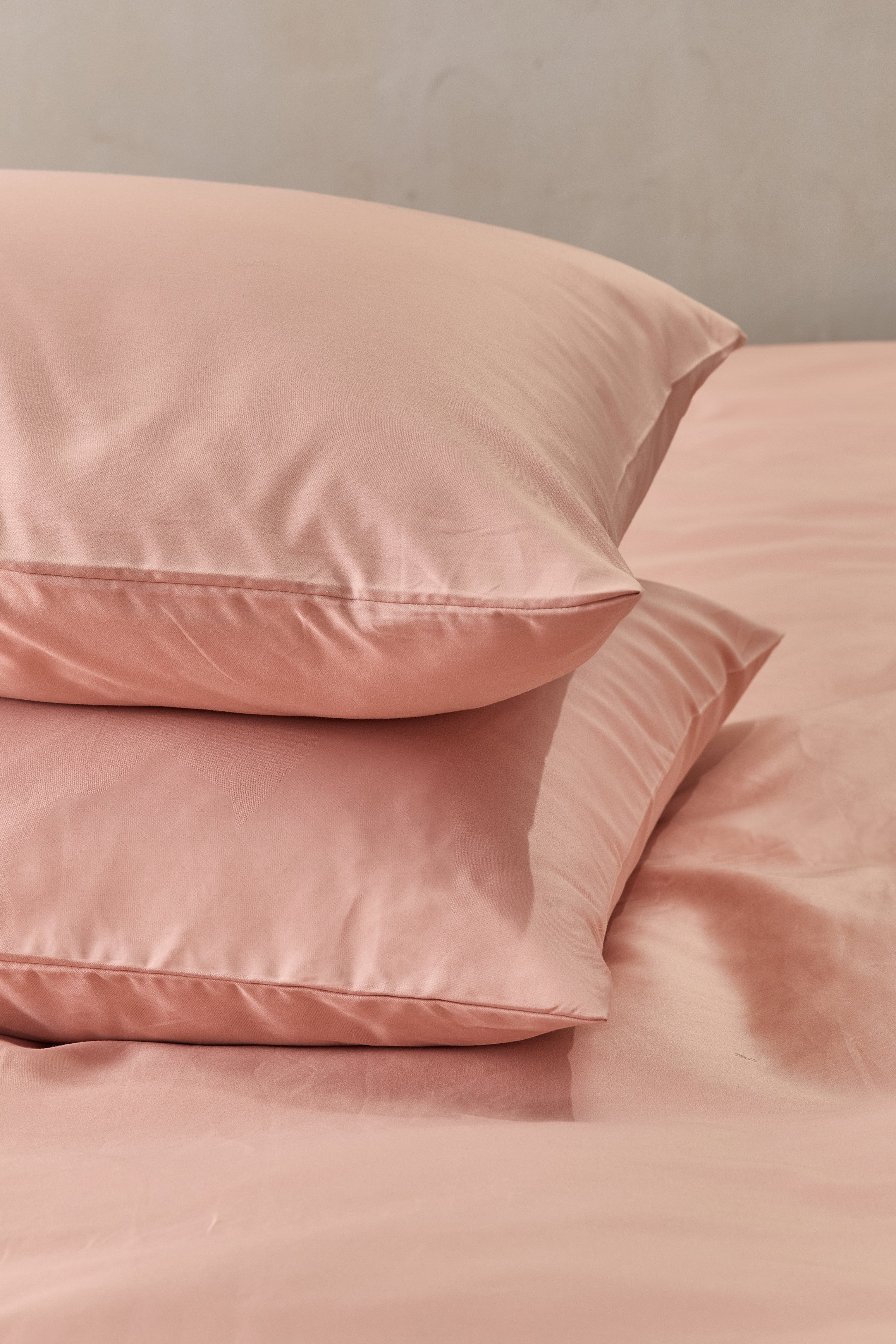 זוג כריות אחת על השניה עם ציפיות כותנה בצבע אפרסק 