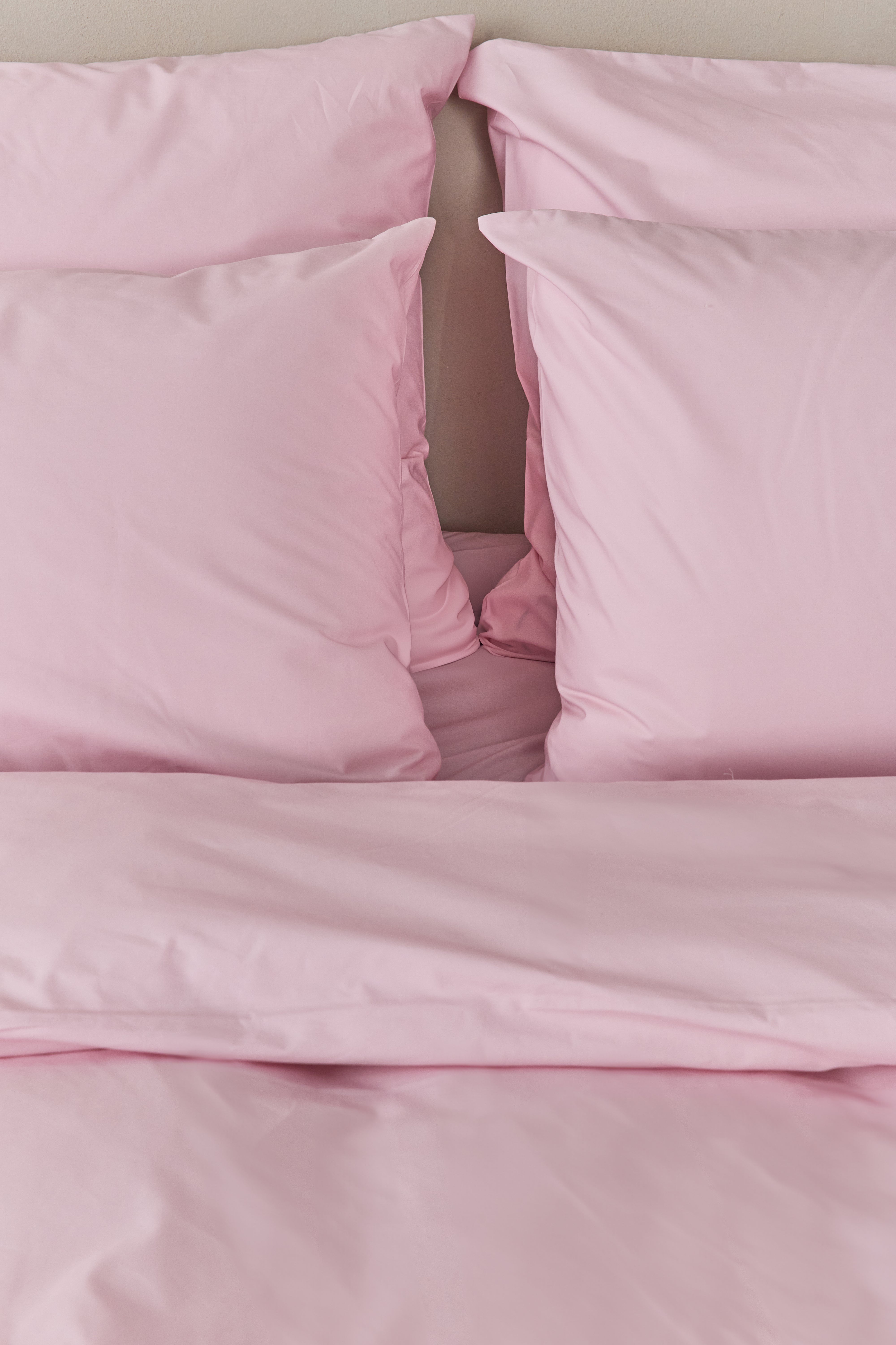 תקריב מיטה זוגית עם סט מצעי כותנה בצבע ורוד בהיר