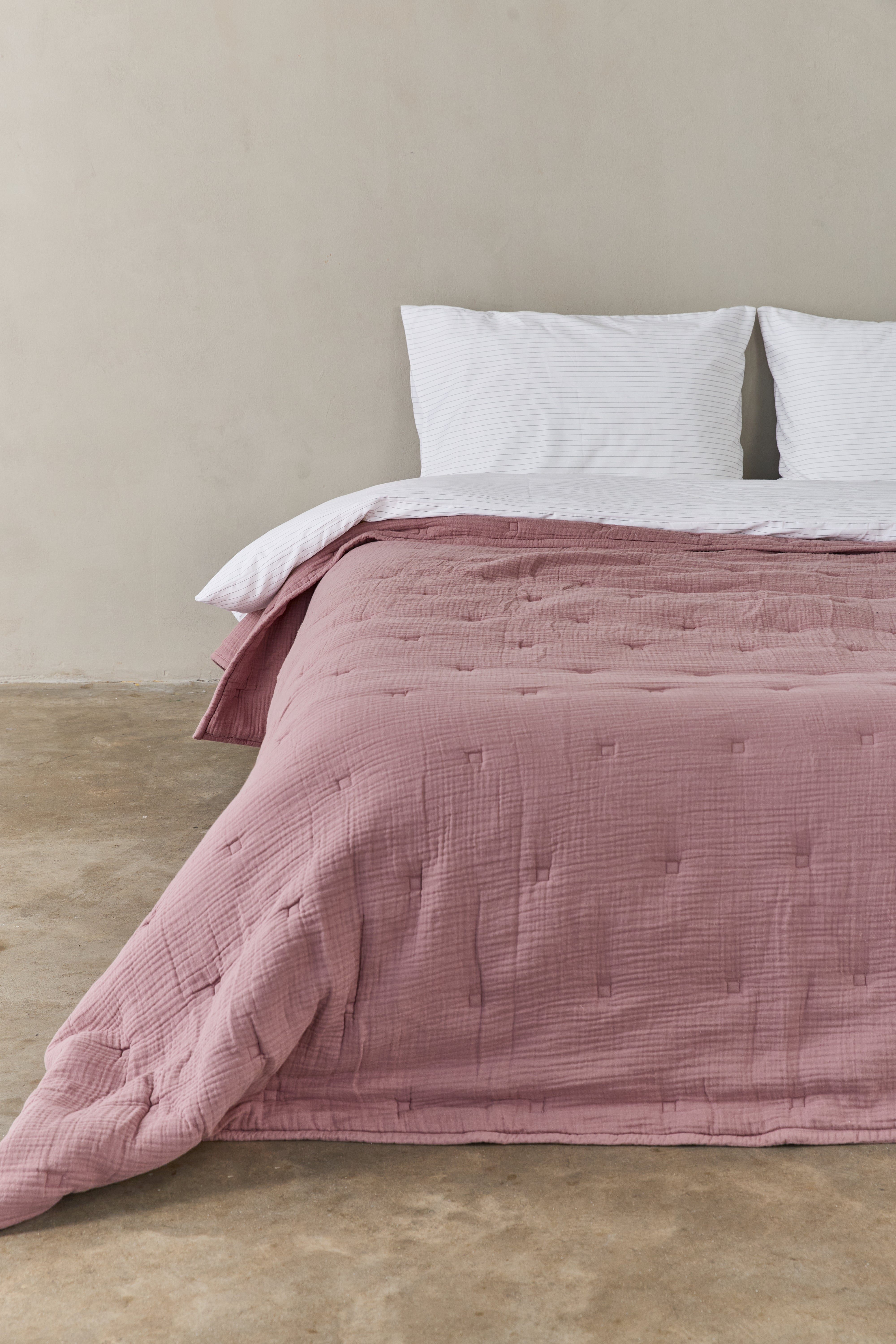 שמיכת פוך מוסלין בצבע ורוד עתיק פרוסה על מיטה זוגית עם מצעים לבנים