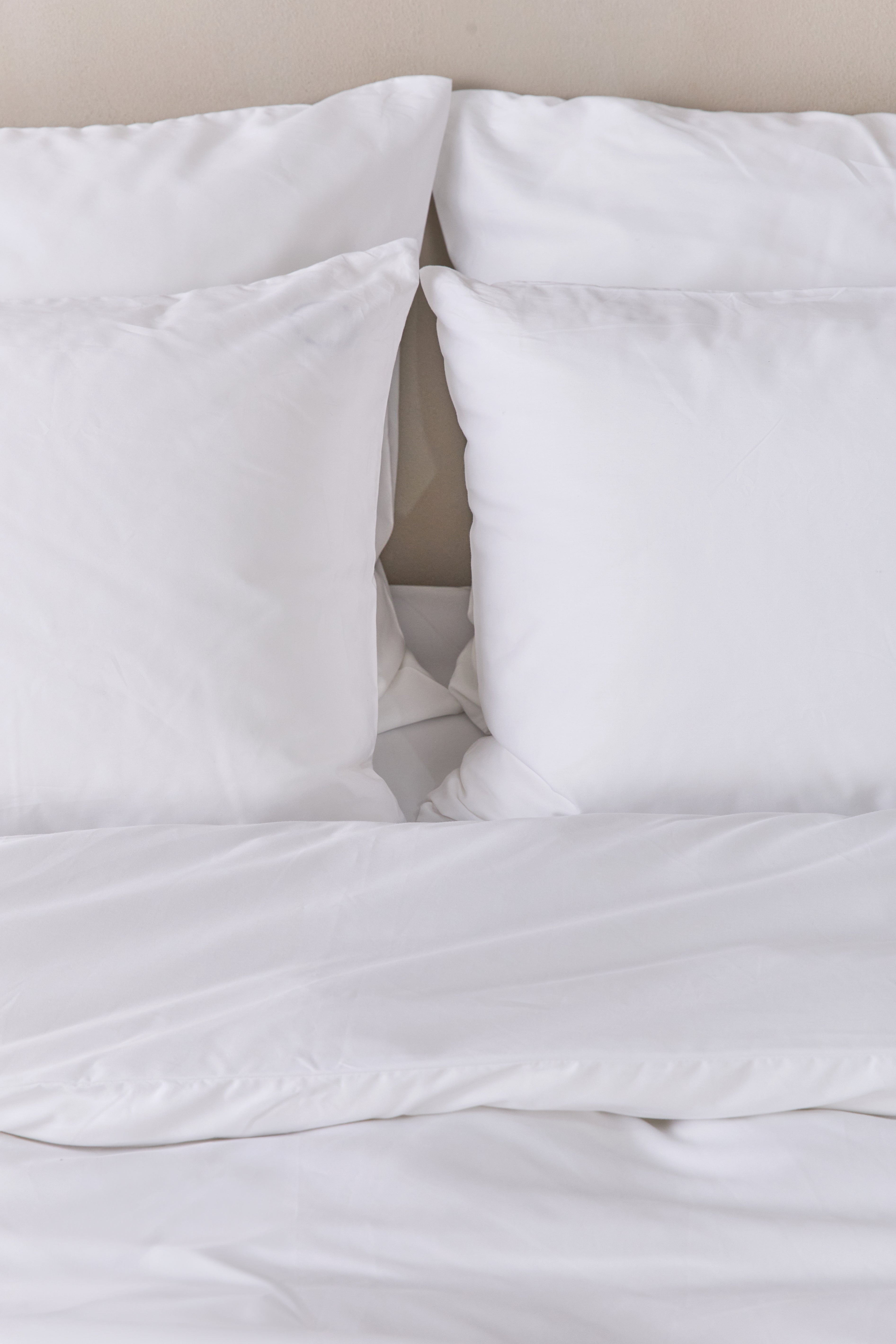 תקריב מיטה עם סט מצעי כותנה בצבע לבן