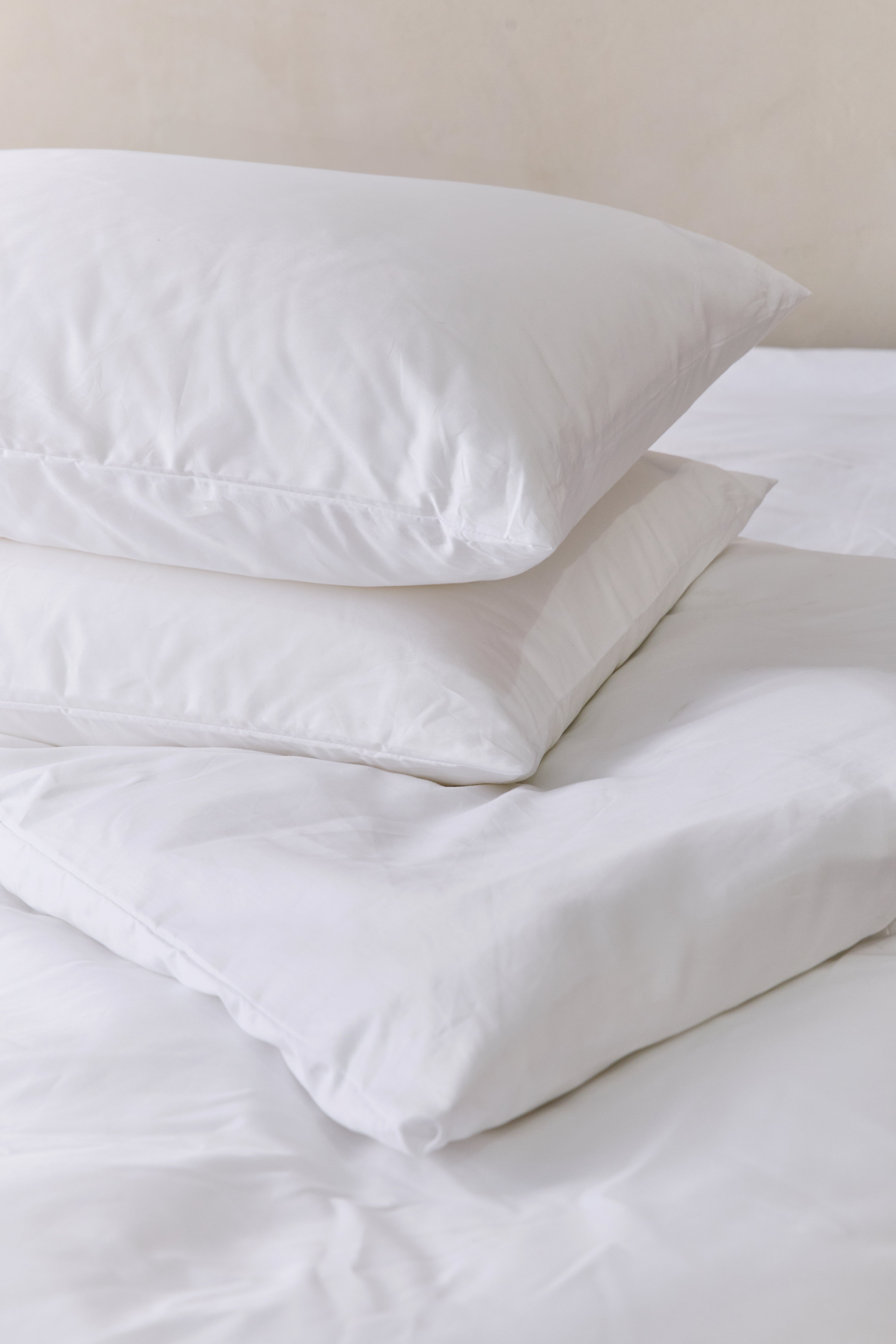 זוג כריות מונחות אחת על השניה עם מצעי כותנה לבנים 