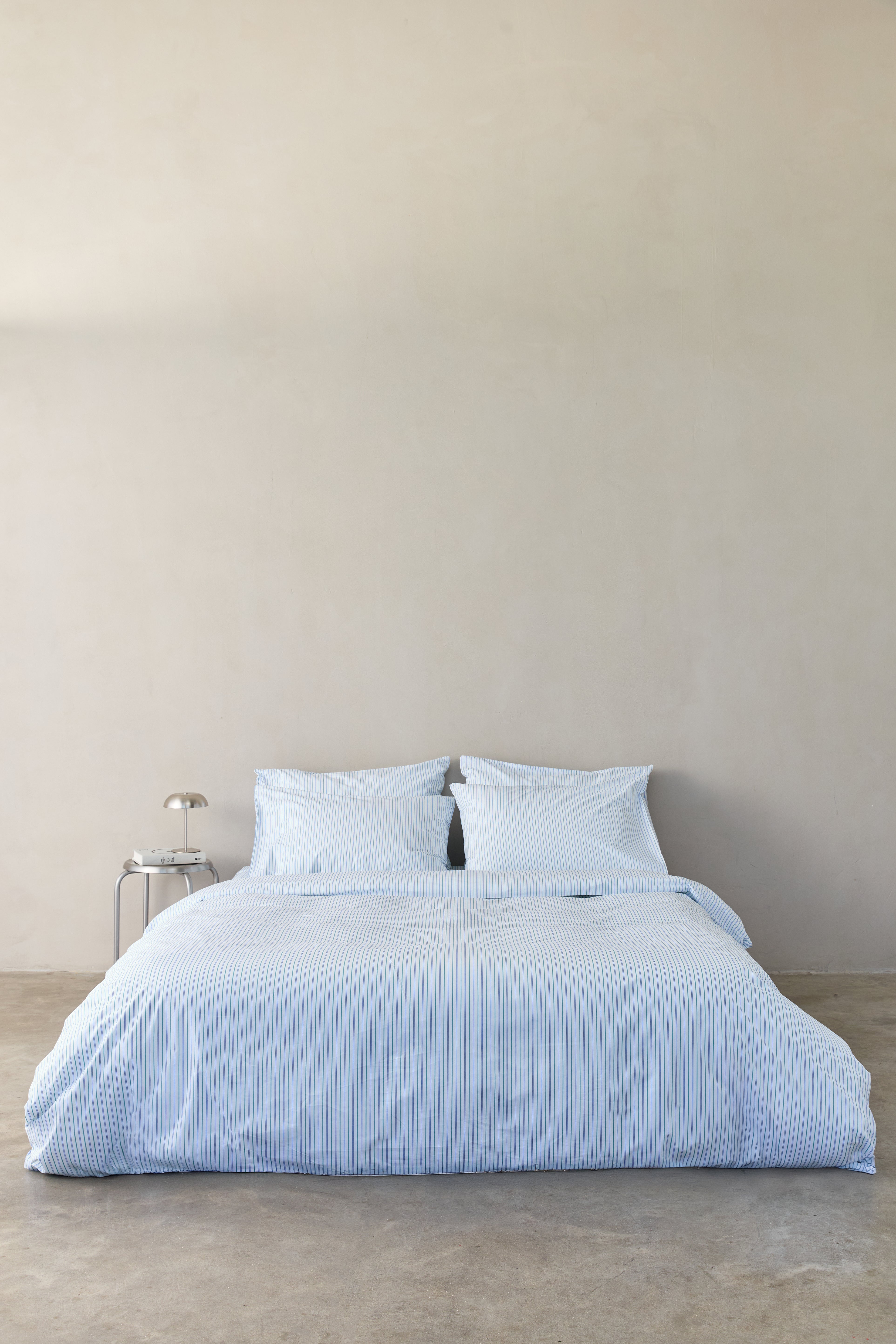 מיטה זוגית עם מצעי פרקל בצבע לבן עם פסים כחולים וירוקים