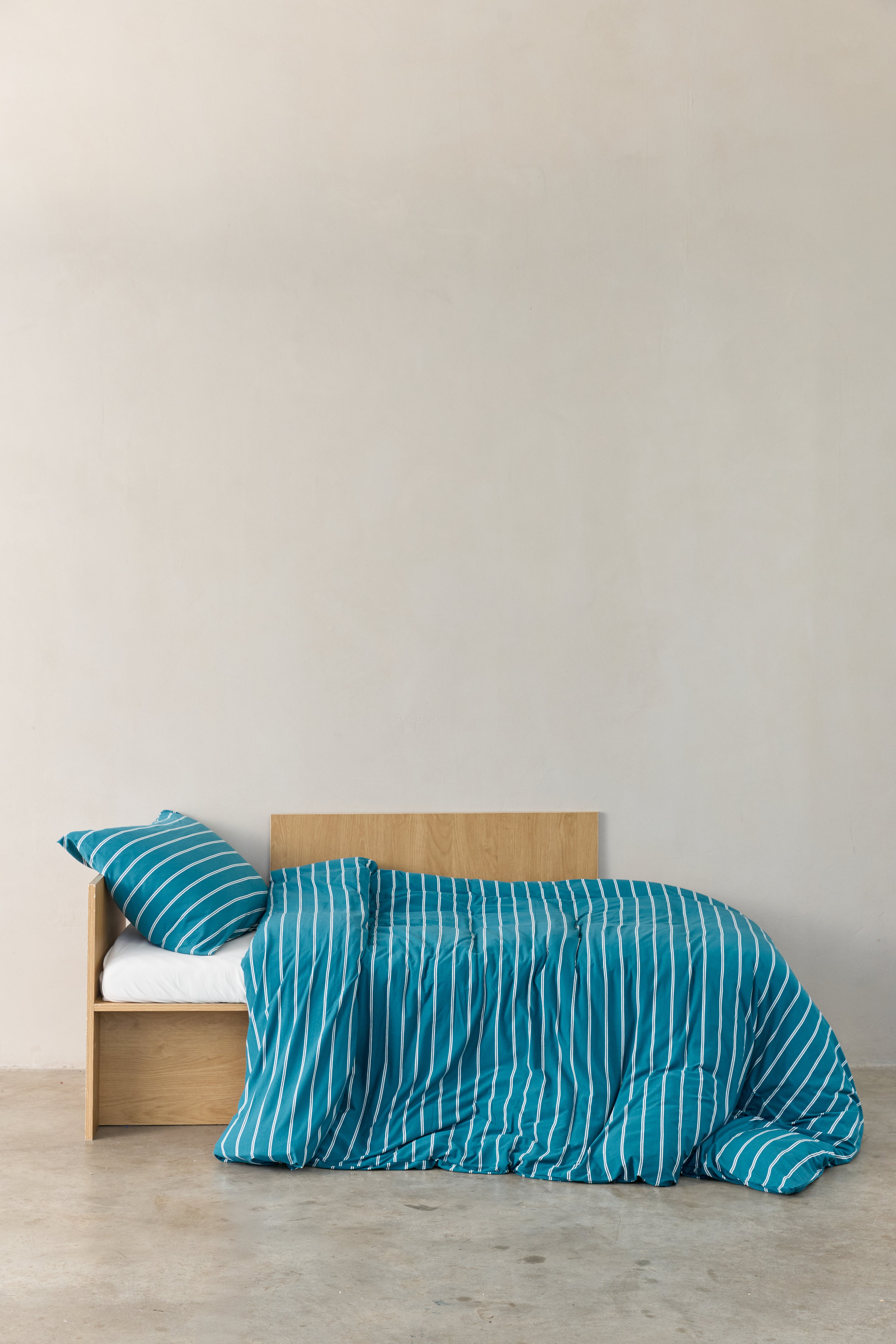 מיטת ילדים עם מצעי ג'רסי במבוק בצבע טורקיז עם פסים לבנים, הסדין לבן חלק