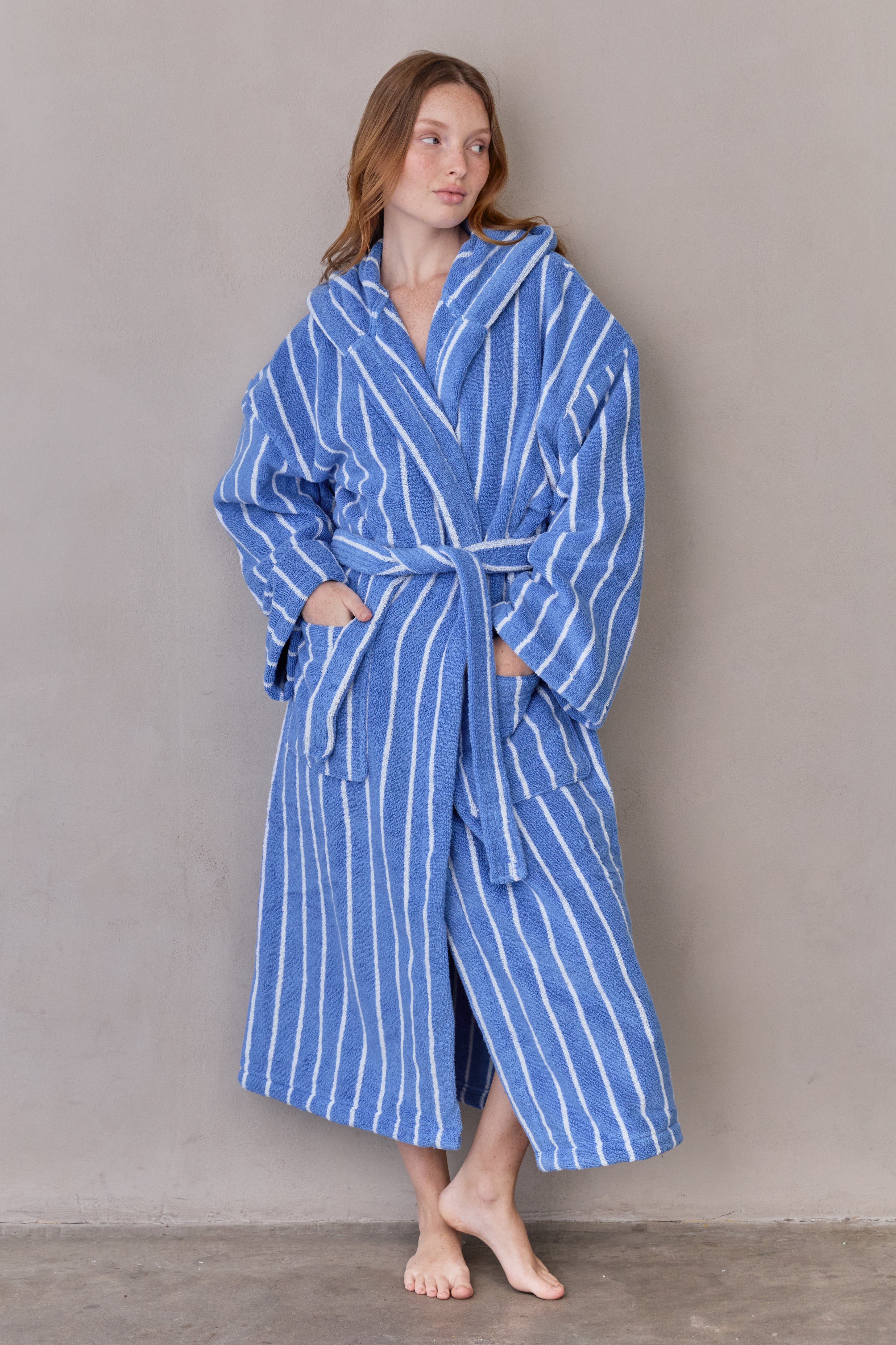 דוגמנית עומדת עם חלוק כחול עם פסים לבנים וידיים בכיסים