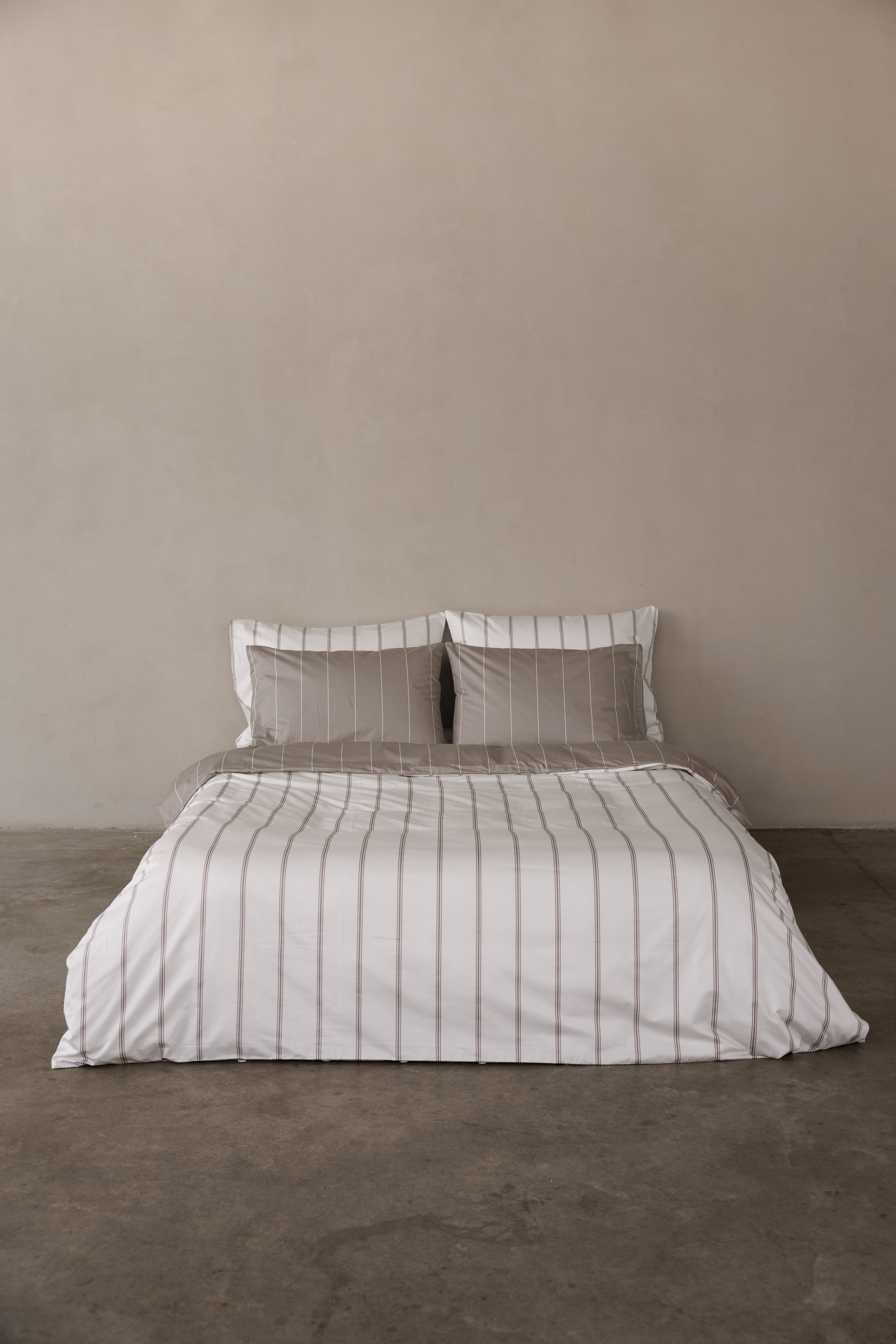 מיטה זוגית עם מצעי סאטן 500, כריות אחוריות לבנות עם פסים בצבע אבן , כריות קדמיות בצבע אבן עם פסים לבנים. הציפה דו צדדית צד אחד אבן עם פסים לבנים וצד אחד לבן עם פסים אבן